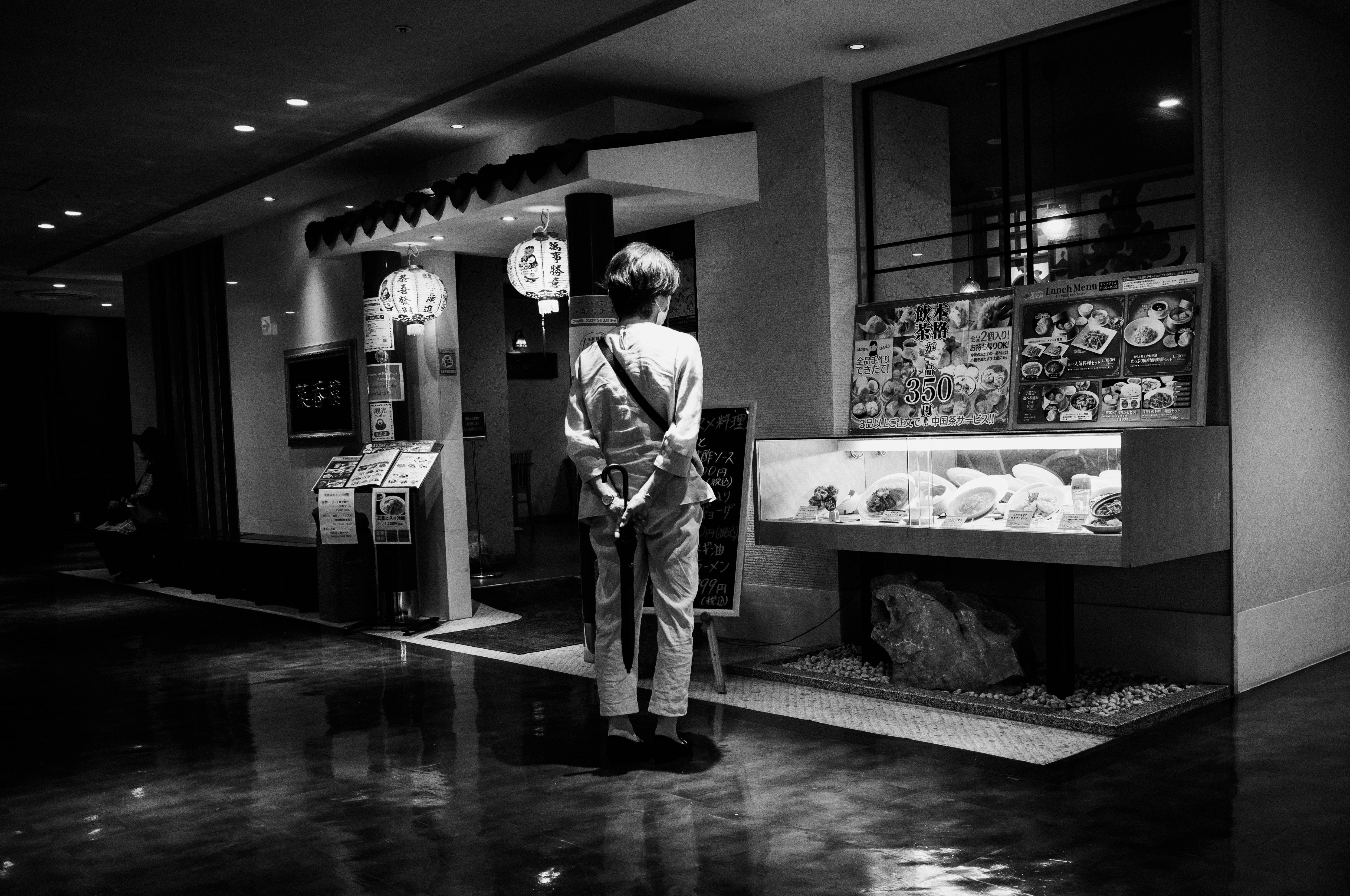 Black-and-white indoor scene of a person standing by a display case