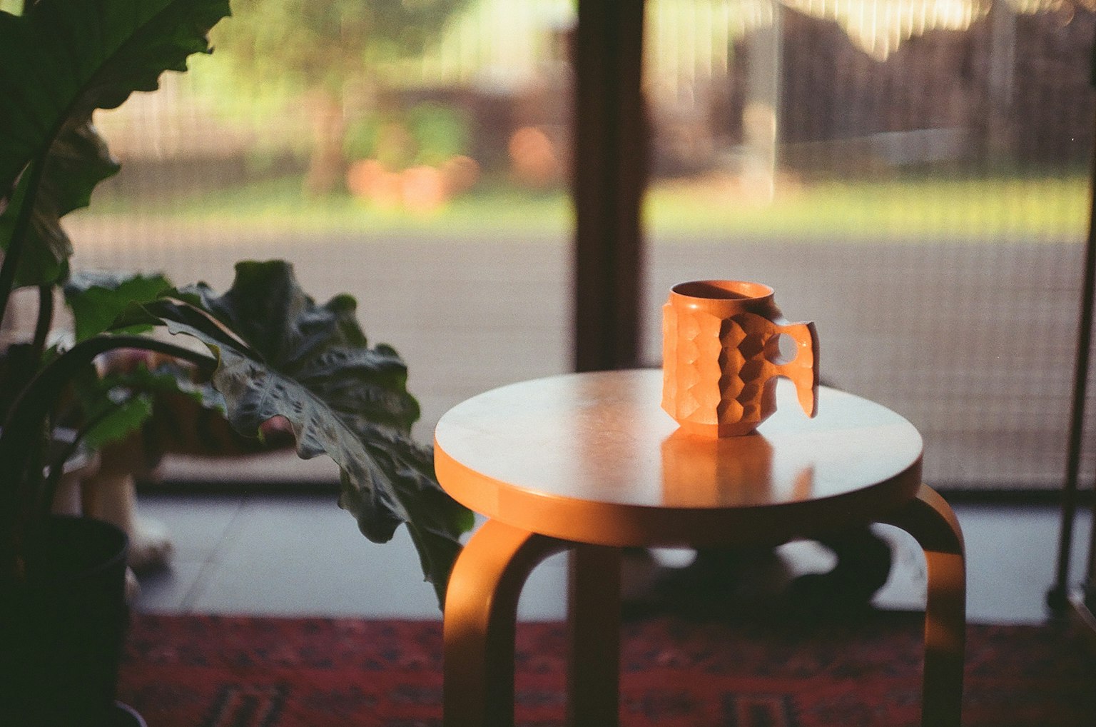 Mug en céramique sur une table en bois avec une plante verte à proximité