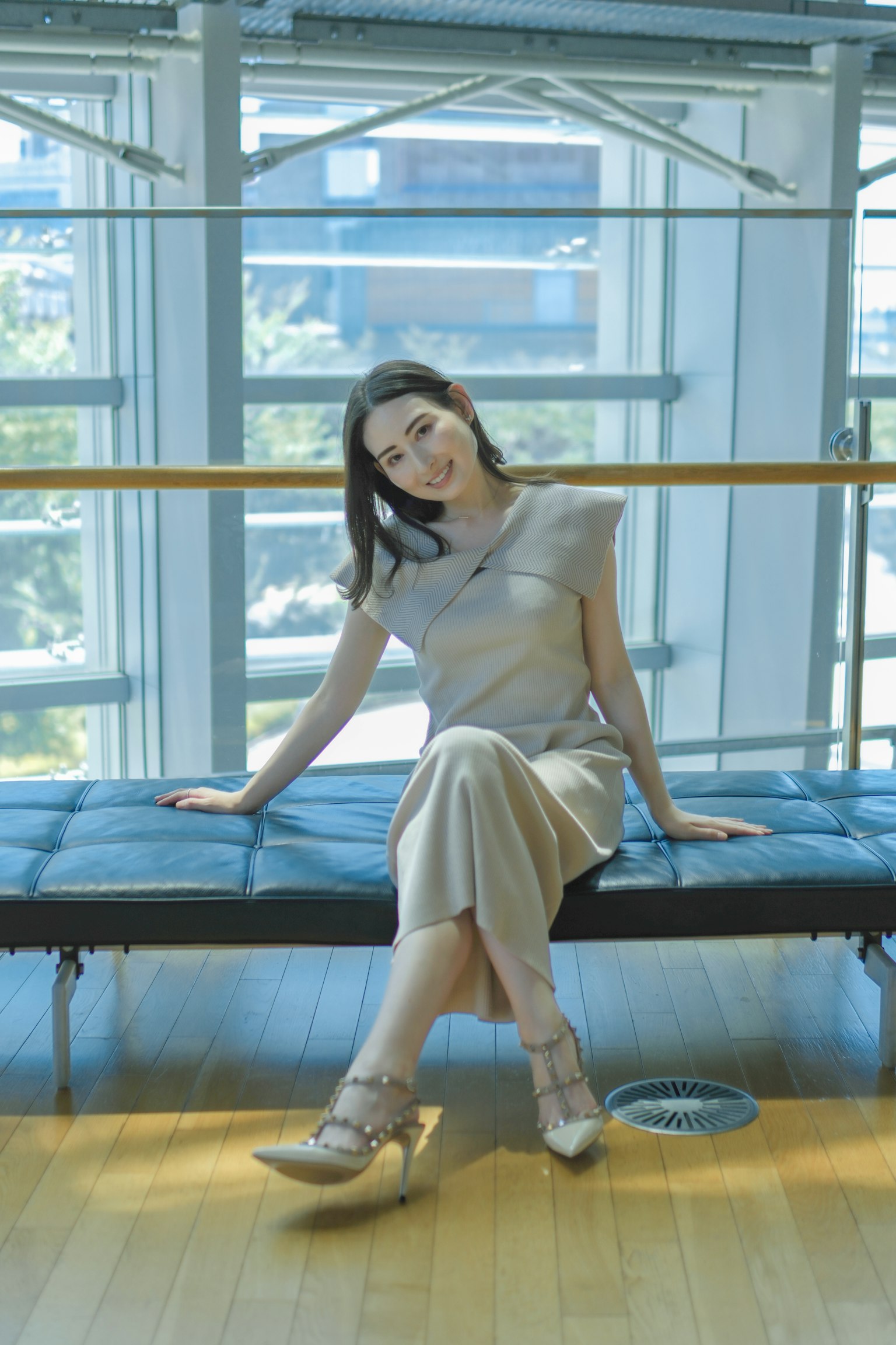 一位穿着优雅的女性坐在明亮室内的长椅上