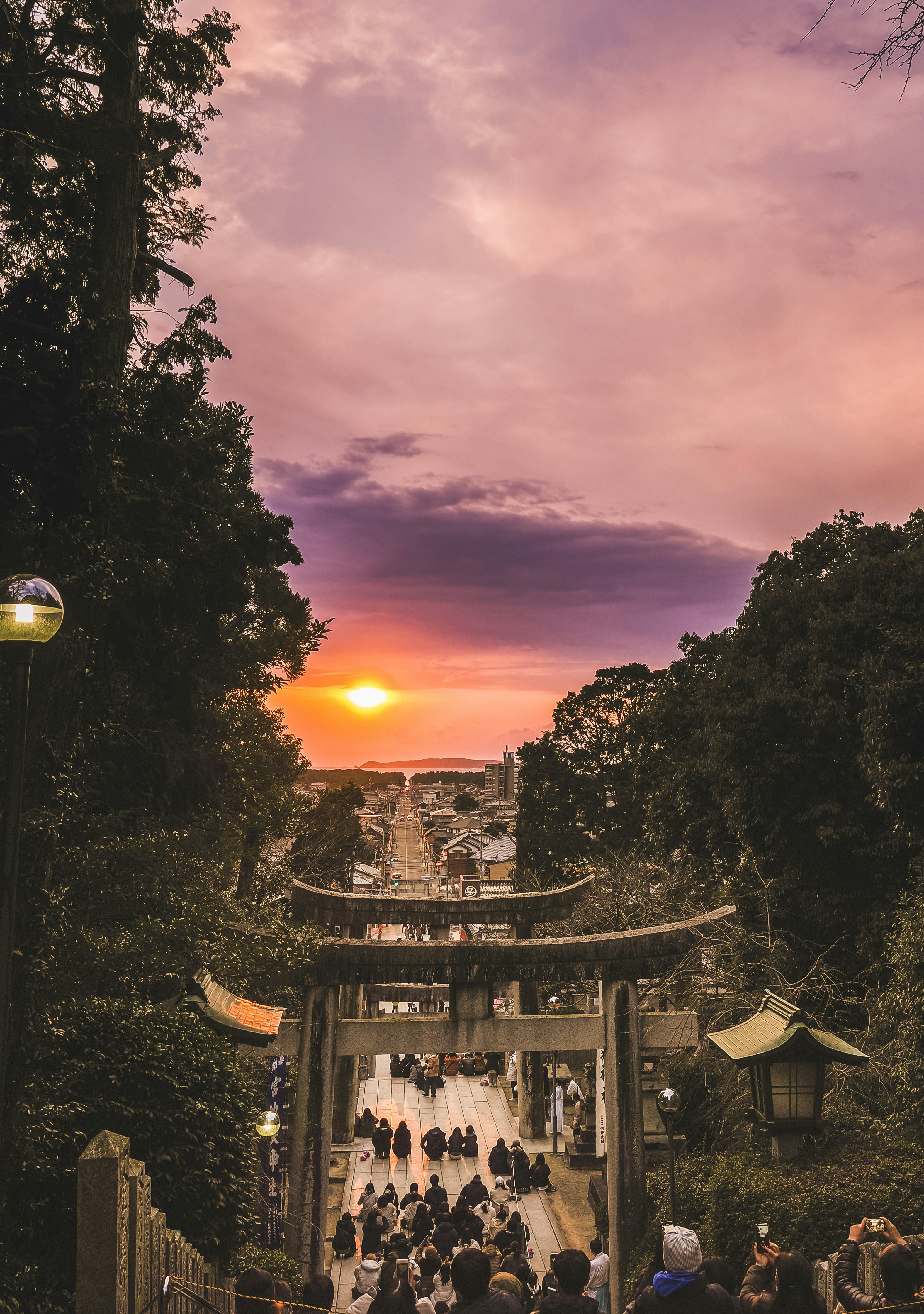 Đám đông trên lối vào đền thờ với cổng torii lúc hoàng hôn