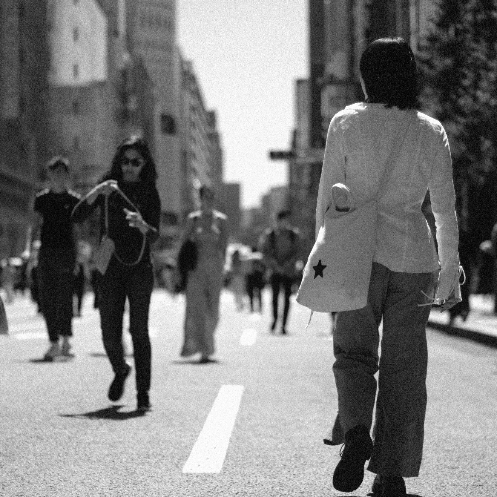 白黒の街中を歩く人々と後ろ姿の女性