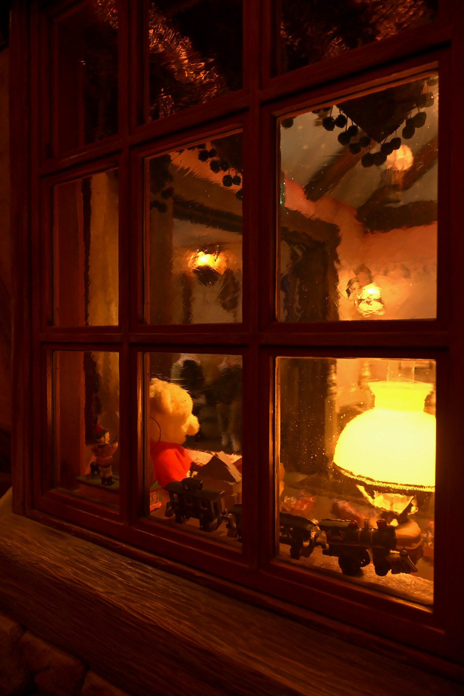 Chambre chaleureusement éclairée vue à travers une fenêtre avec un ours en peluche et une lampe