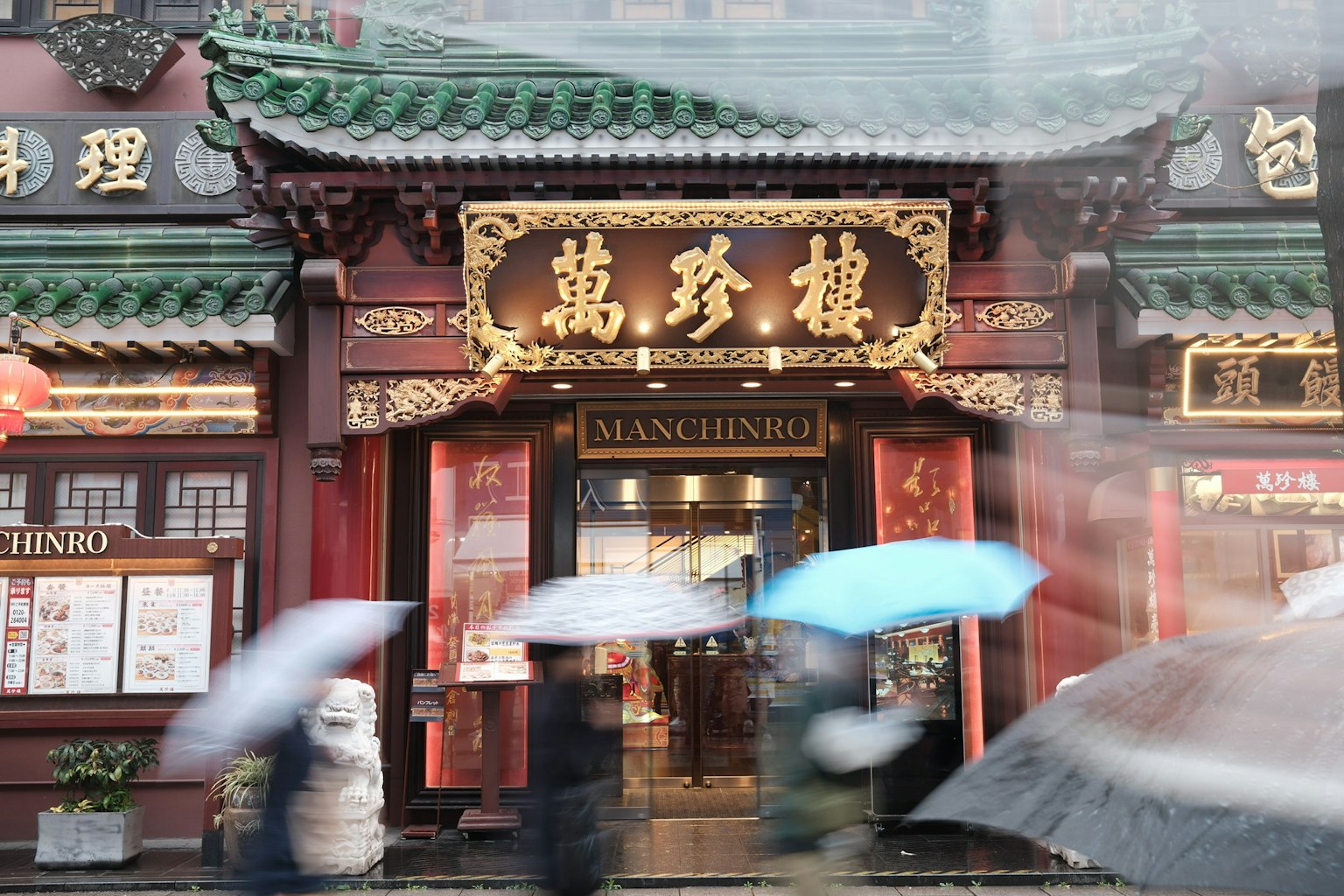 Facciata di un ristorante cinese tradizionale sotto la pioggia con decorazioni intricate e un'insegna prominente