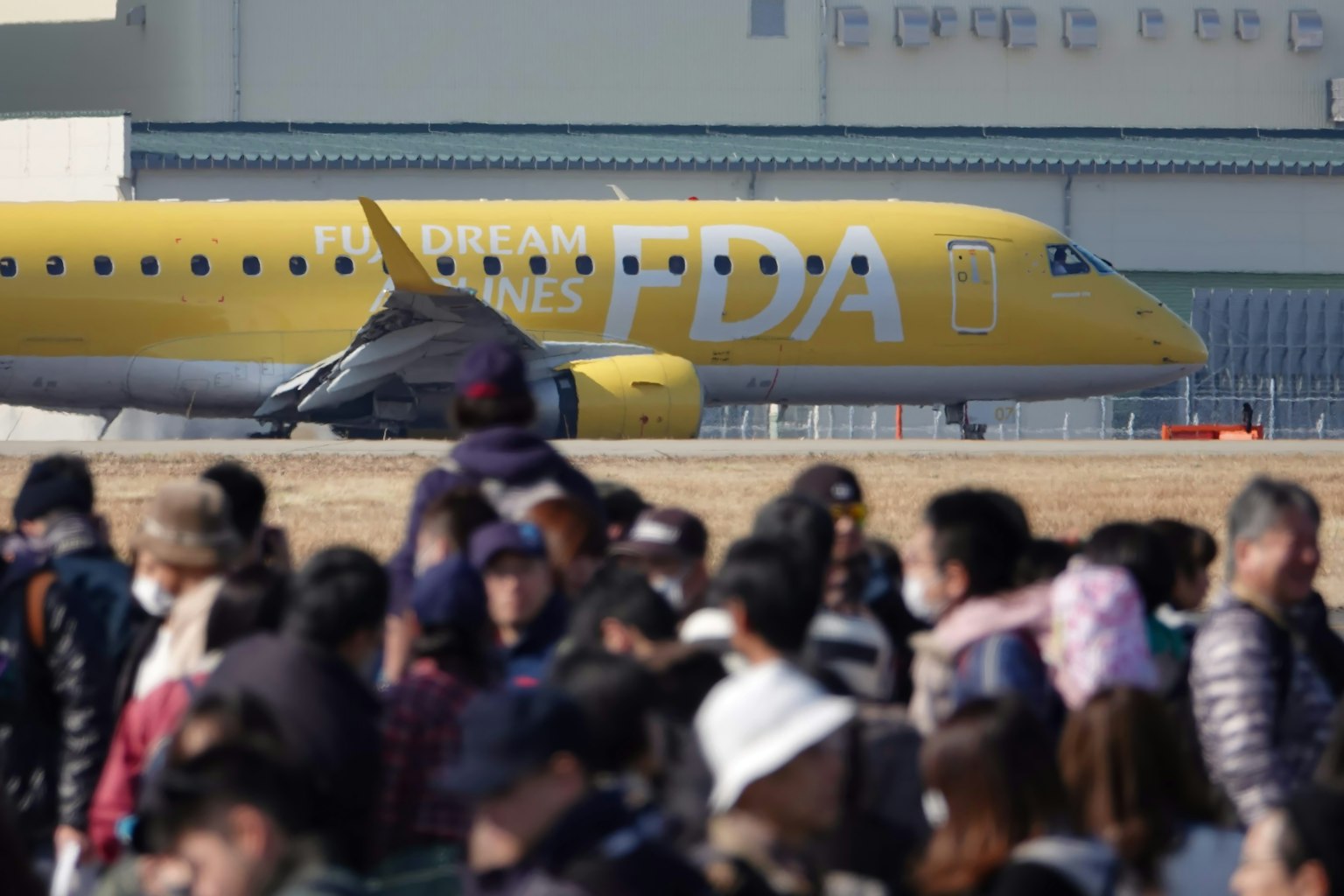Foule de personnes devant un avion jaune de la FDA