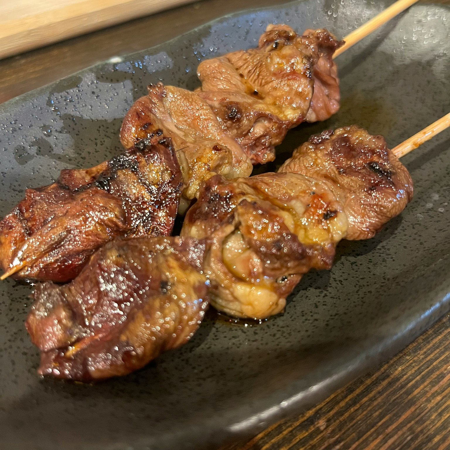 Brochetas de yakitori a la parrilla servidas en un plato negro