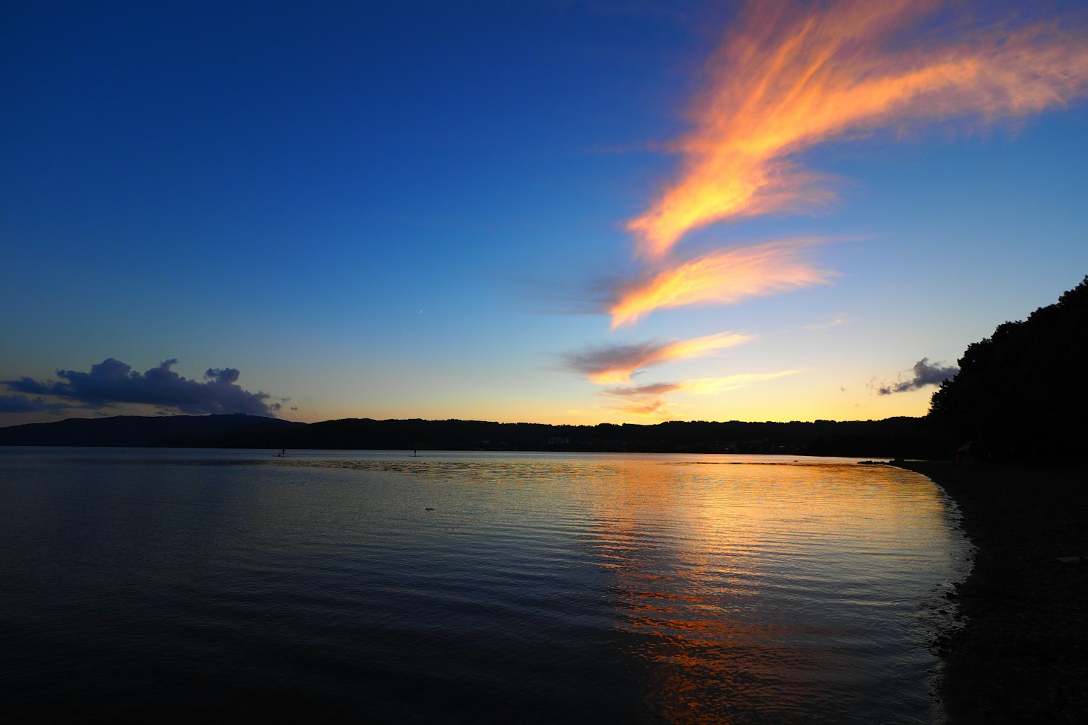 Lago tranquillo al tramonto con nuvole arancioni e riflessi sull'acqua