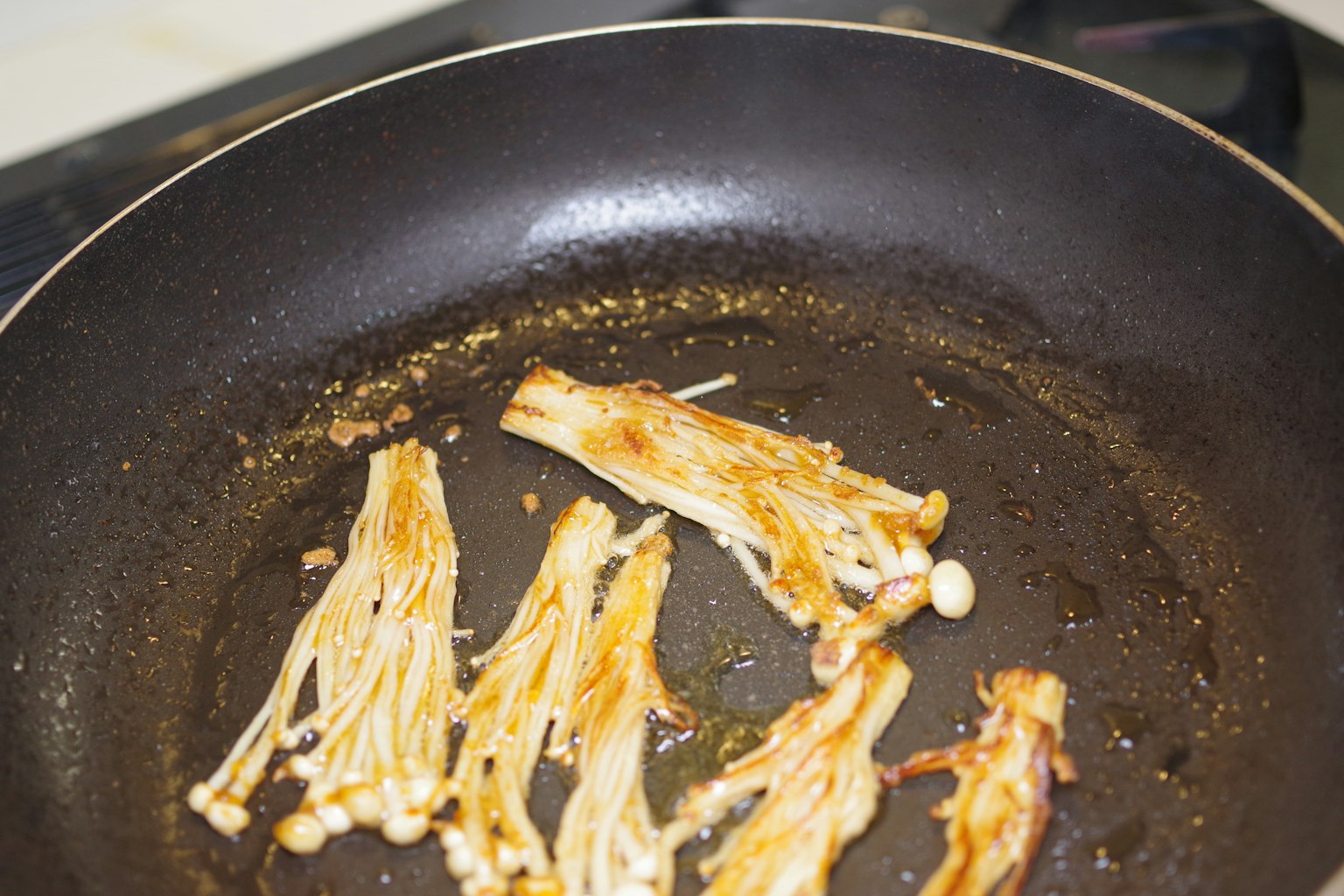 Jamur enoki yang diiris sedang dimasak di wajan