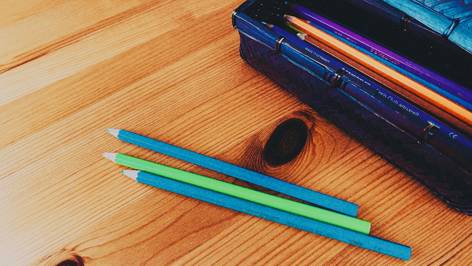 蓝色和绿色彩铅放在木桌上的图片