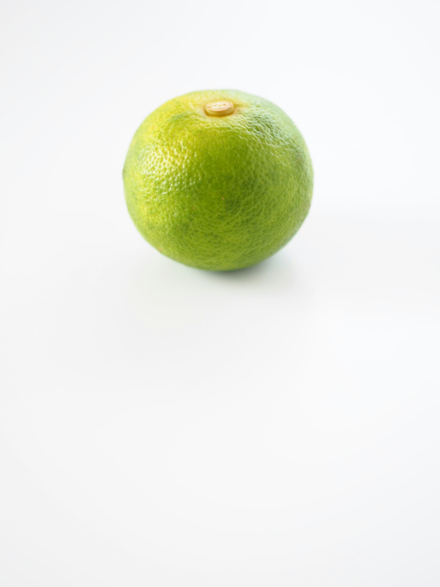 Une orange verte placée sur un fond blanc dans un style minimaliste