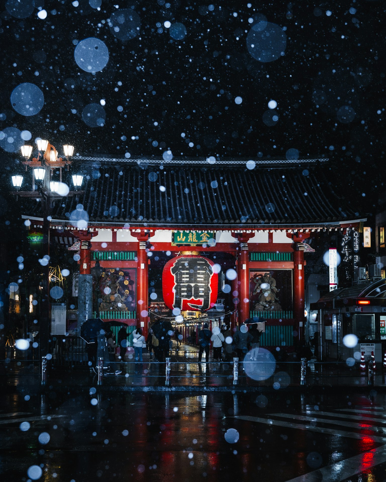 La puerta del trueno roja iluminada en la noche con nieve cayendo y farolas