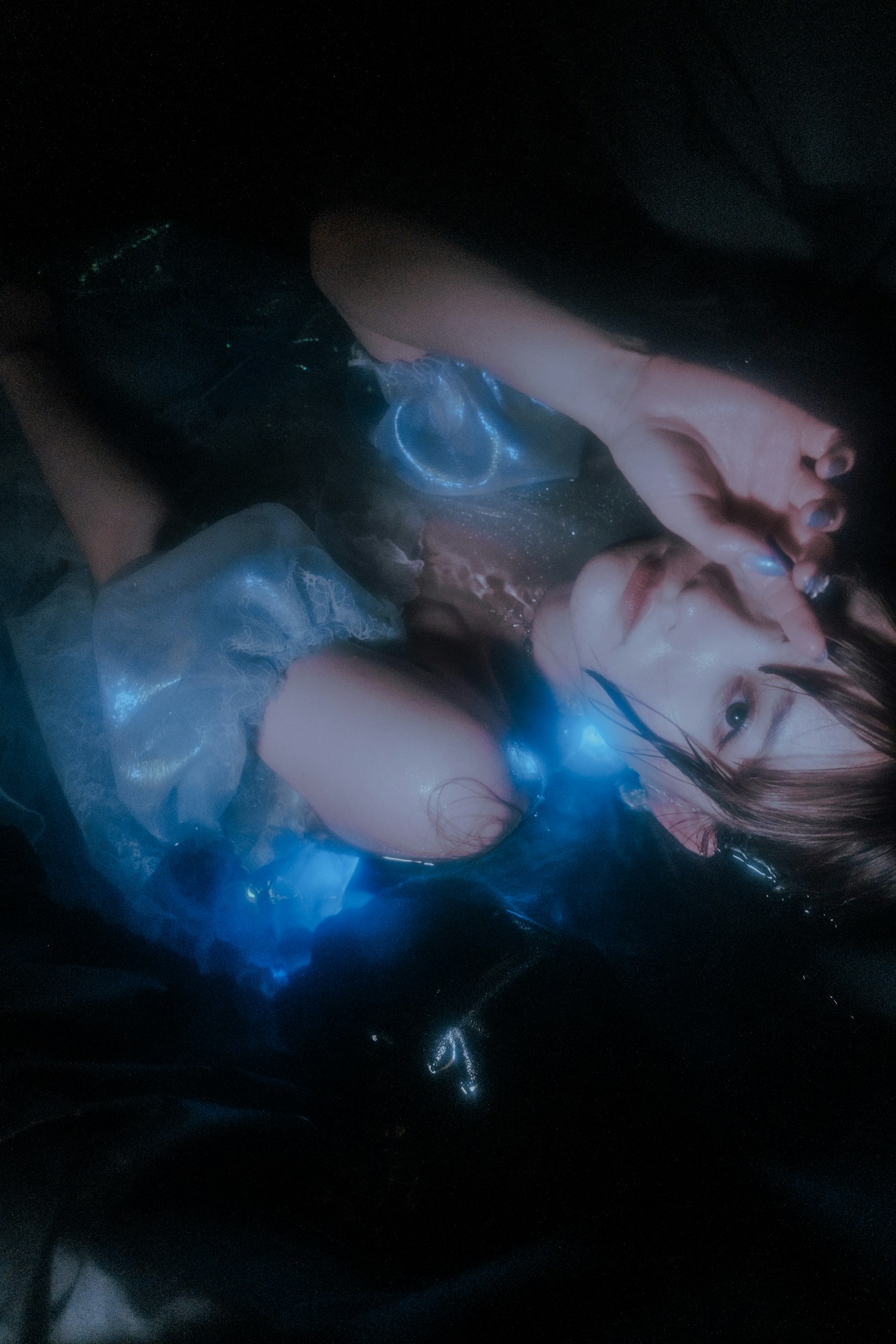 Une femme allongée portant une tenue fantastique émettant une lumière bleue