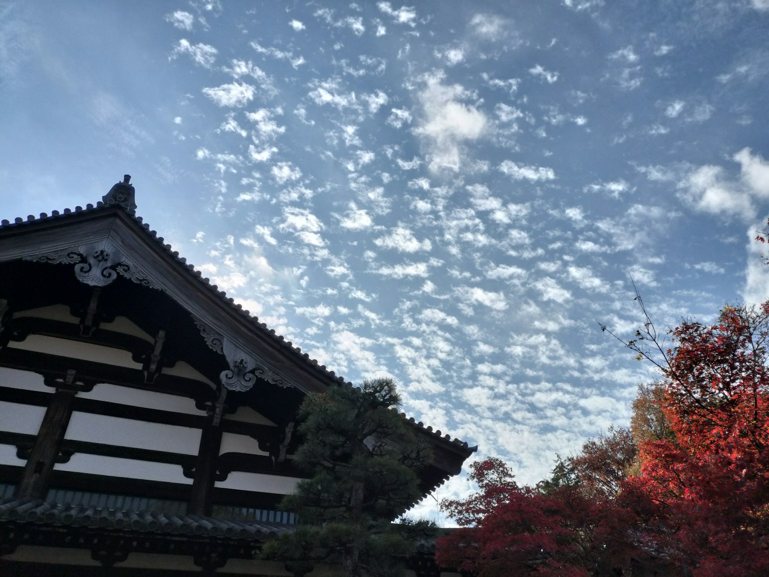 Edificio japonés tradicional bajo un cielo lleno de nubes de otoño y follaje vibrante