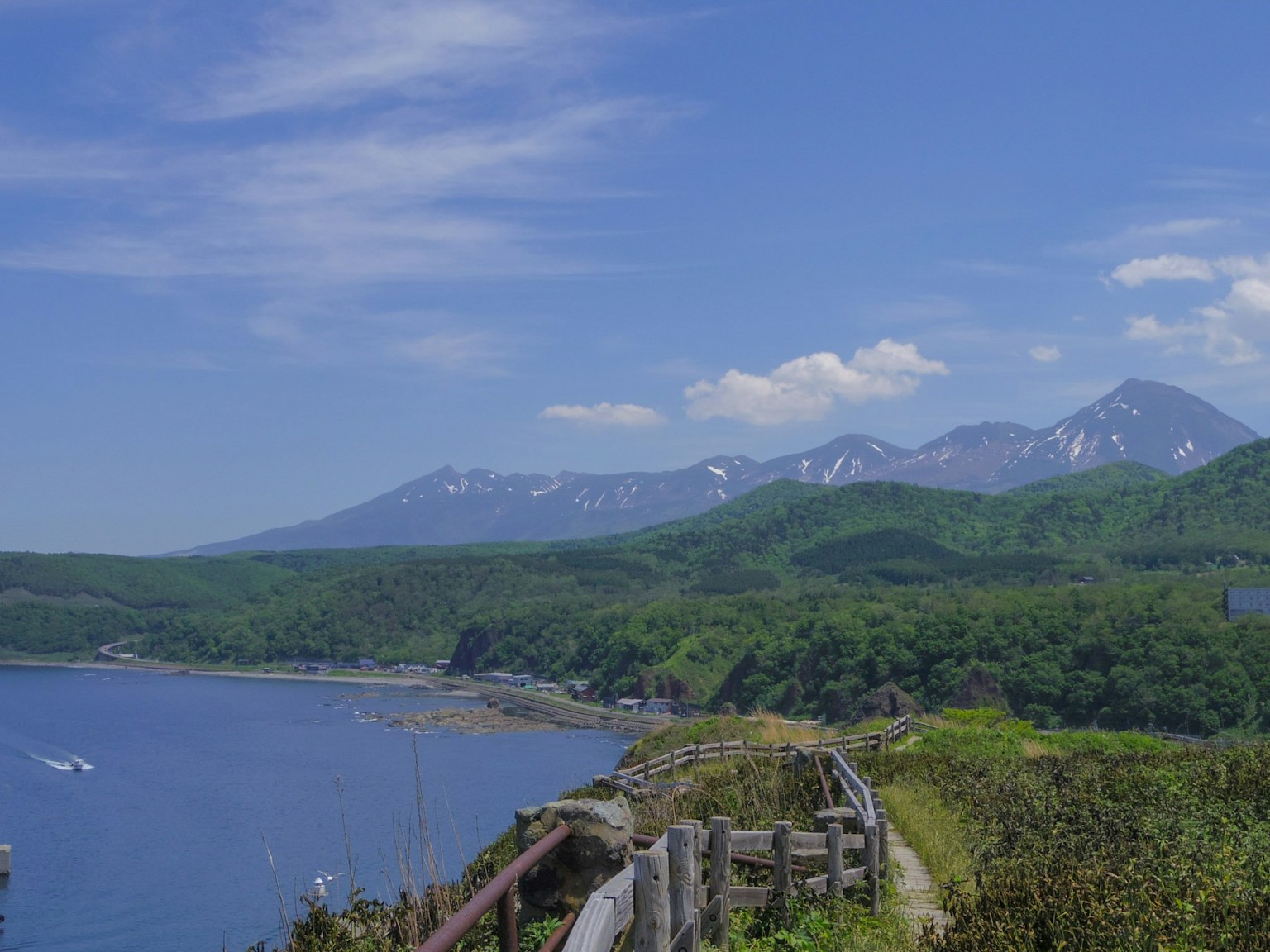 Pemandangan pesisir dengan langit biru dan gunung hijau