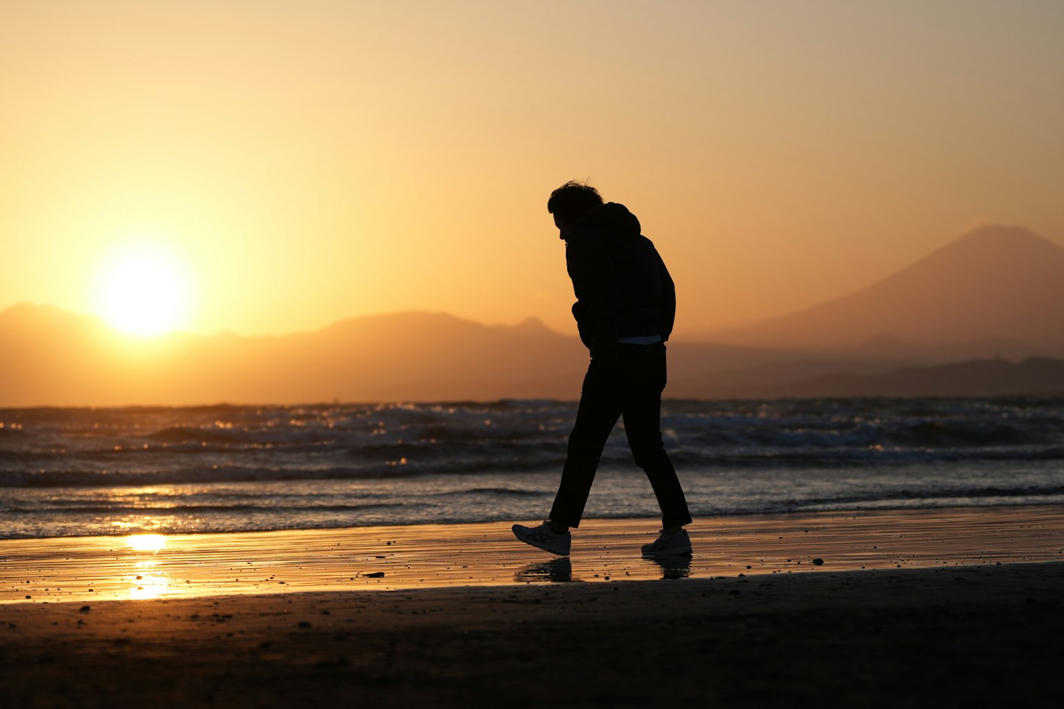 夕阳下在海滩上散步的人影