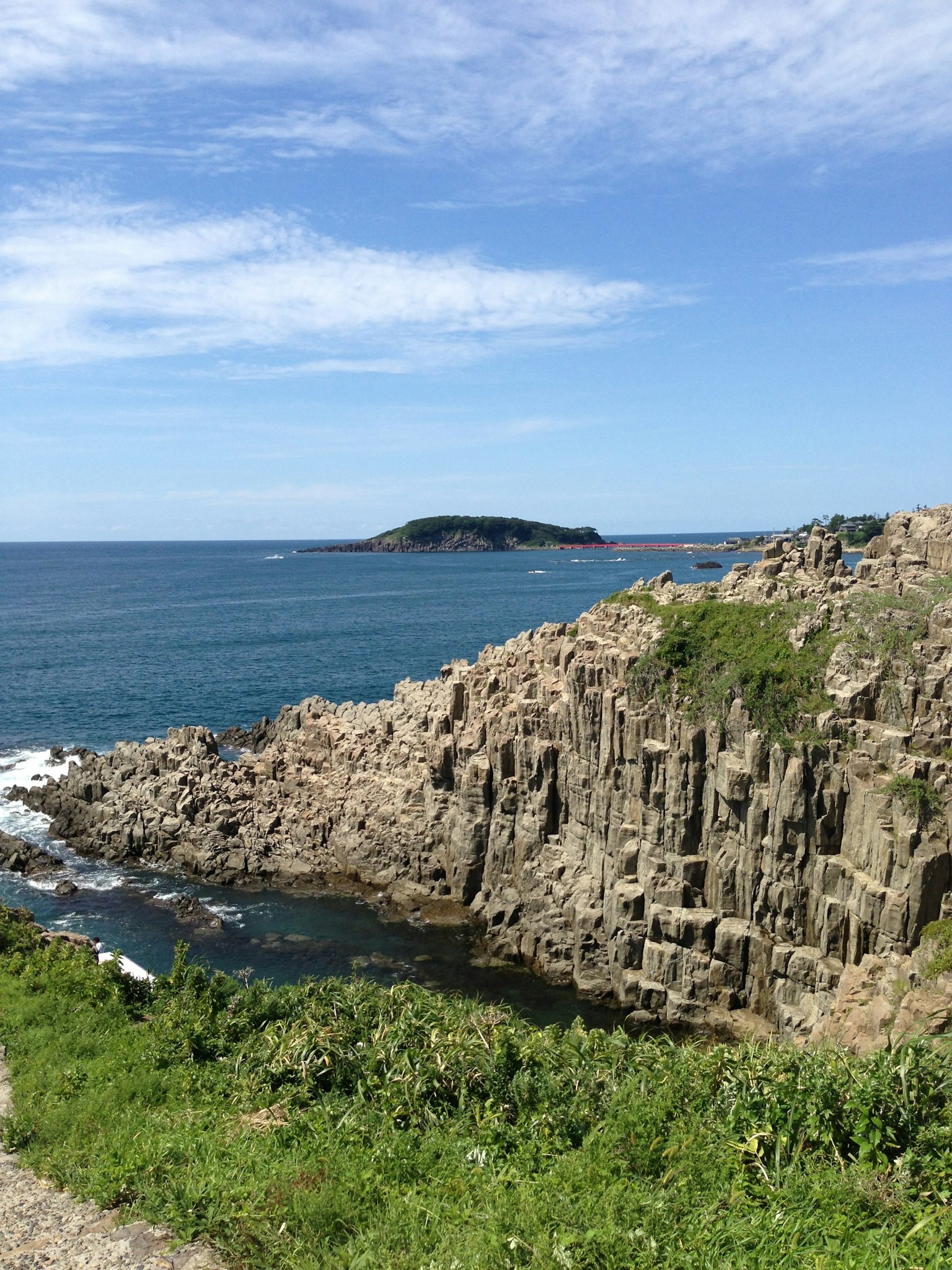 Vista escénica del mar azul y los acantilados rocosos con una pequeña isla a lo lejos