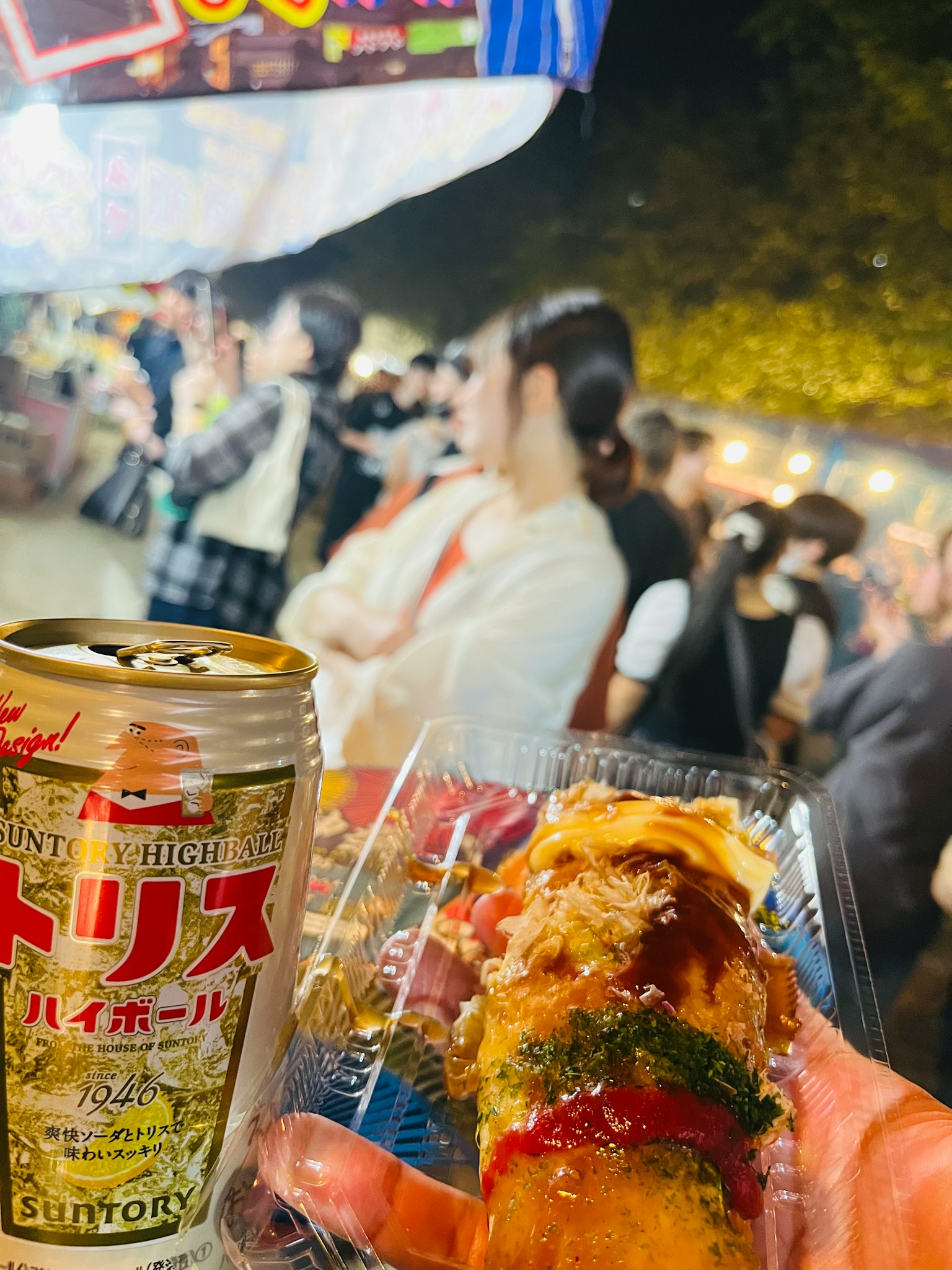 节日中手持食物和啤酒的前景，背景是享受的人们