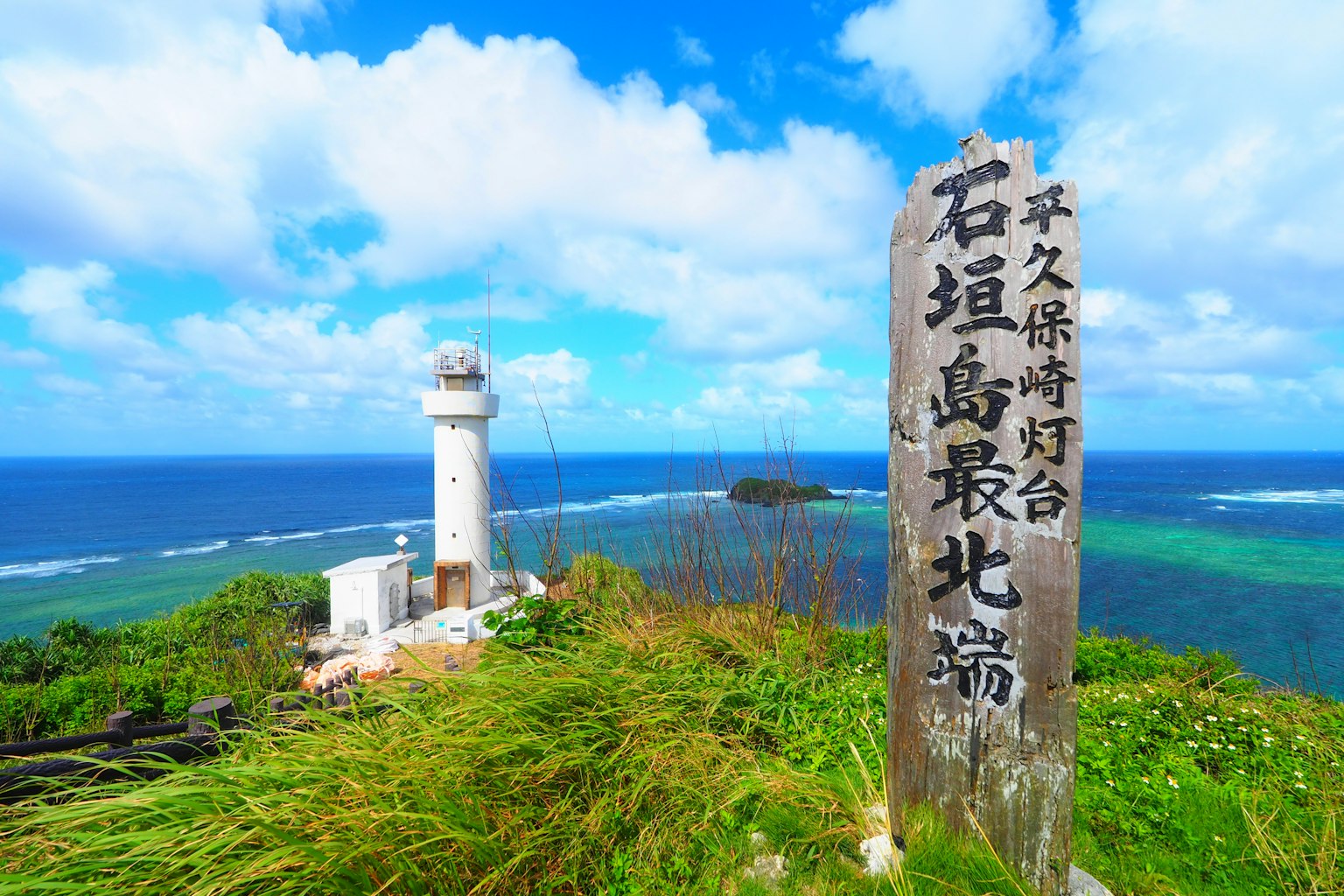 Scenic view of a lighthouse and stone monument against a backdrop of blue sky and ocean