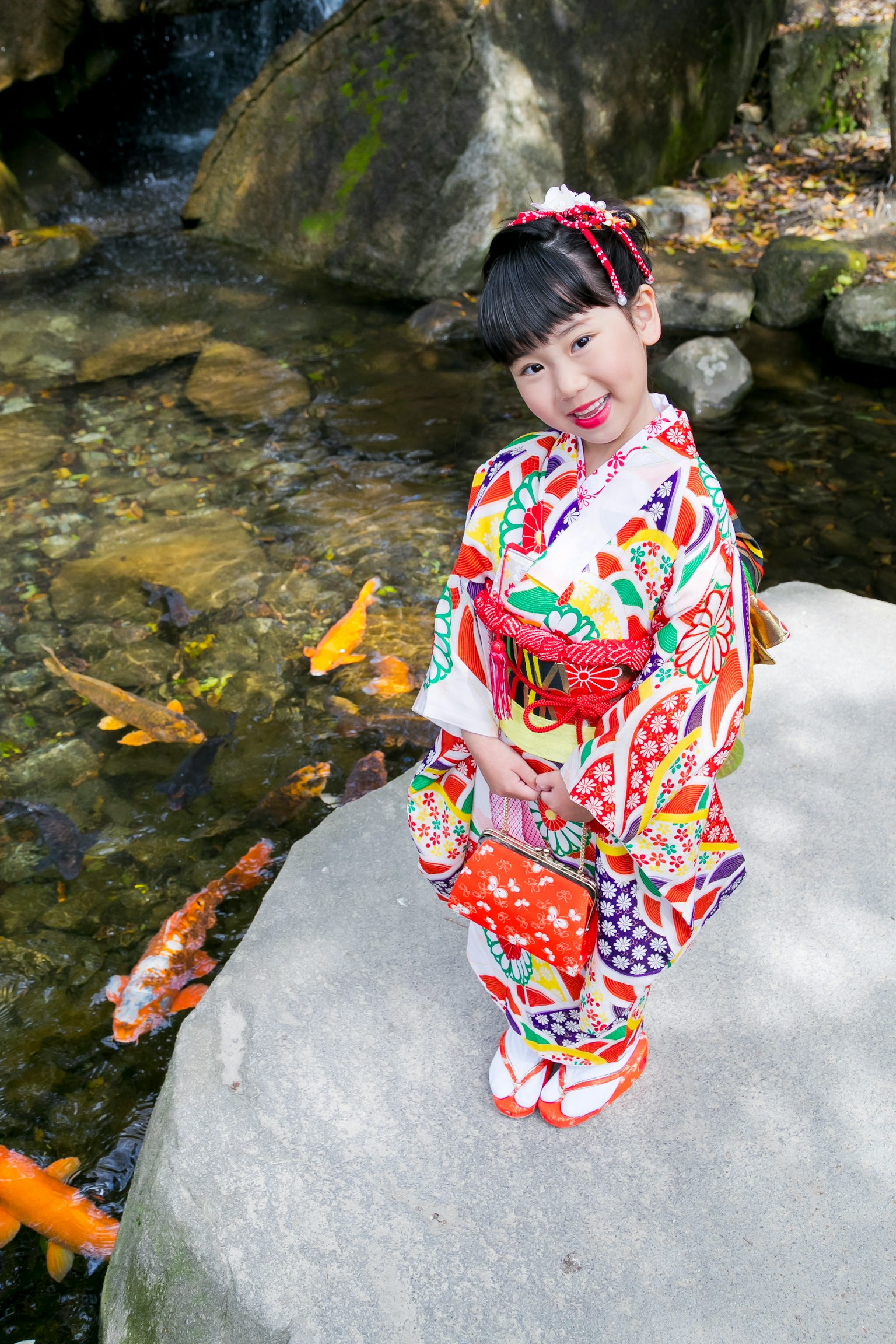 Enfant posant dans un kimono coloré au bord d'un ruisseau