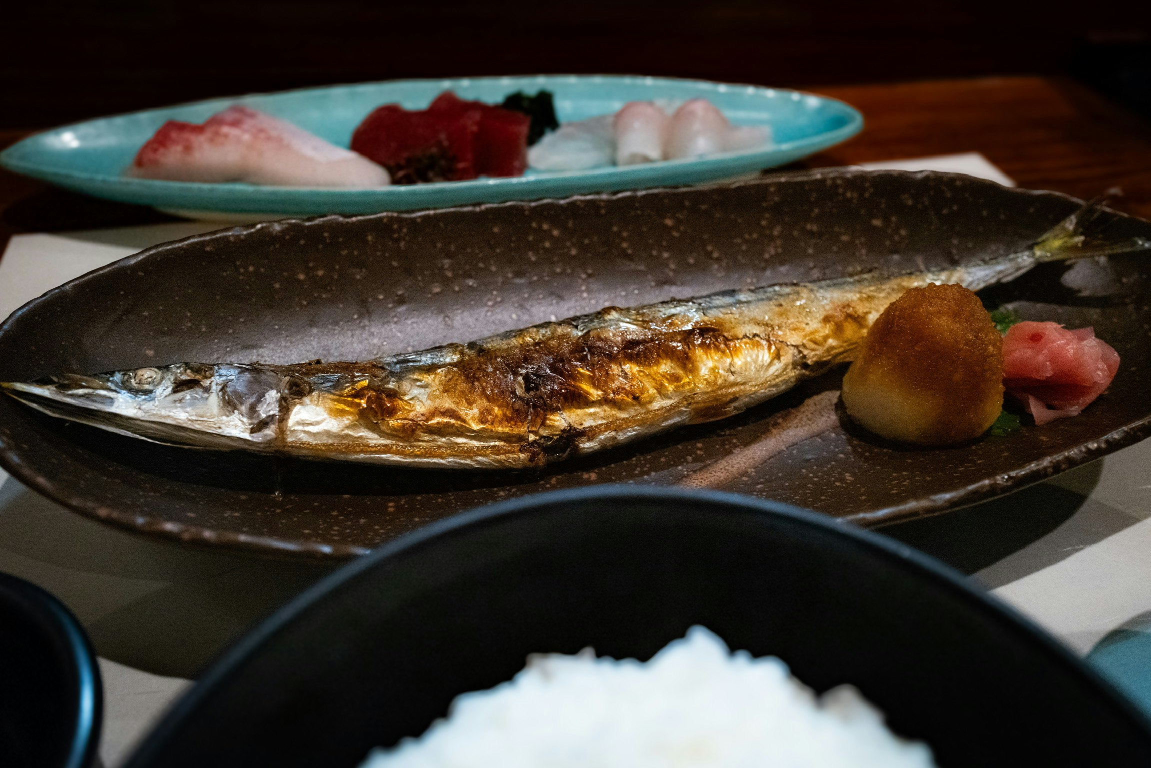 焼き魚の皿とご飯が並ぶ食卓