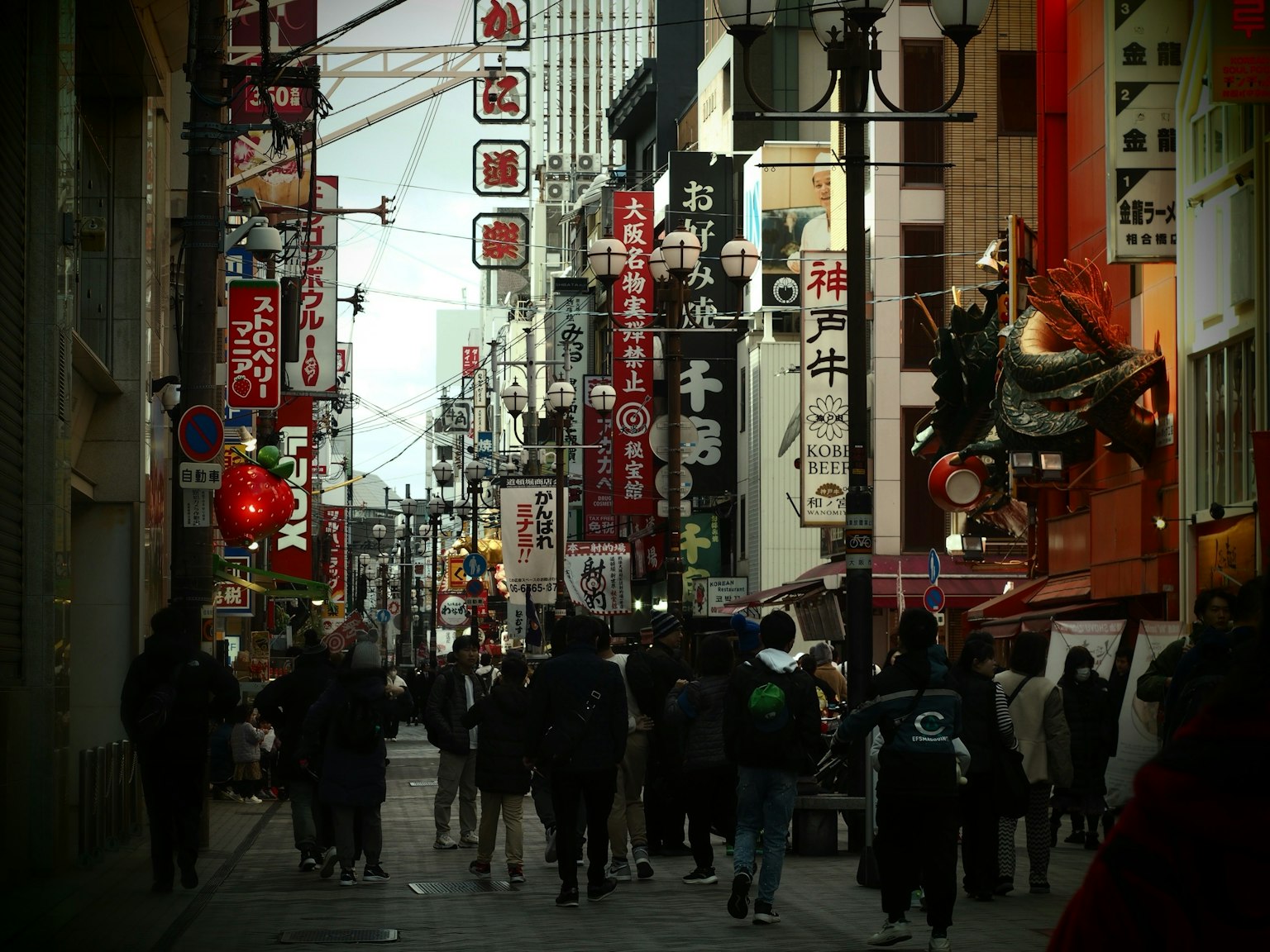 Lebhafte Straßenszene mit Menschen, die gehen Großes Fischschild und bunte Laternen fallen auf