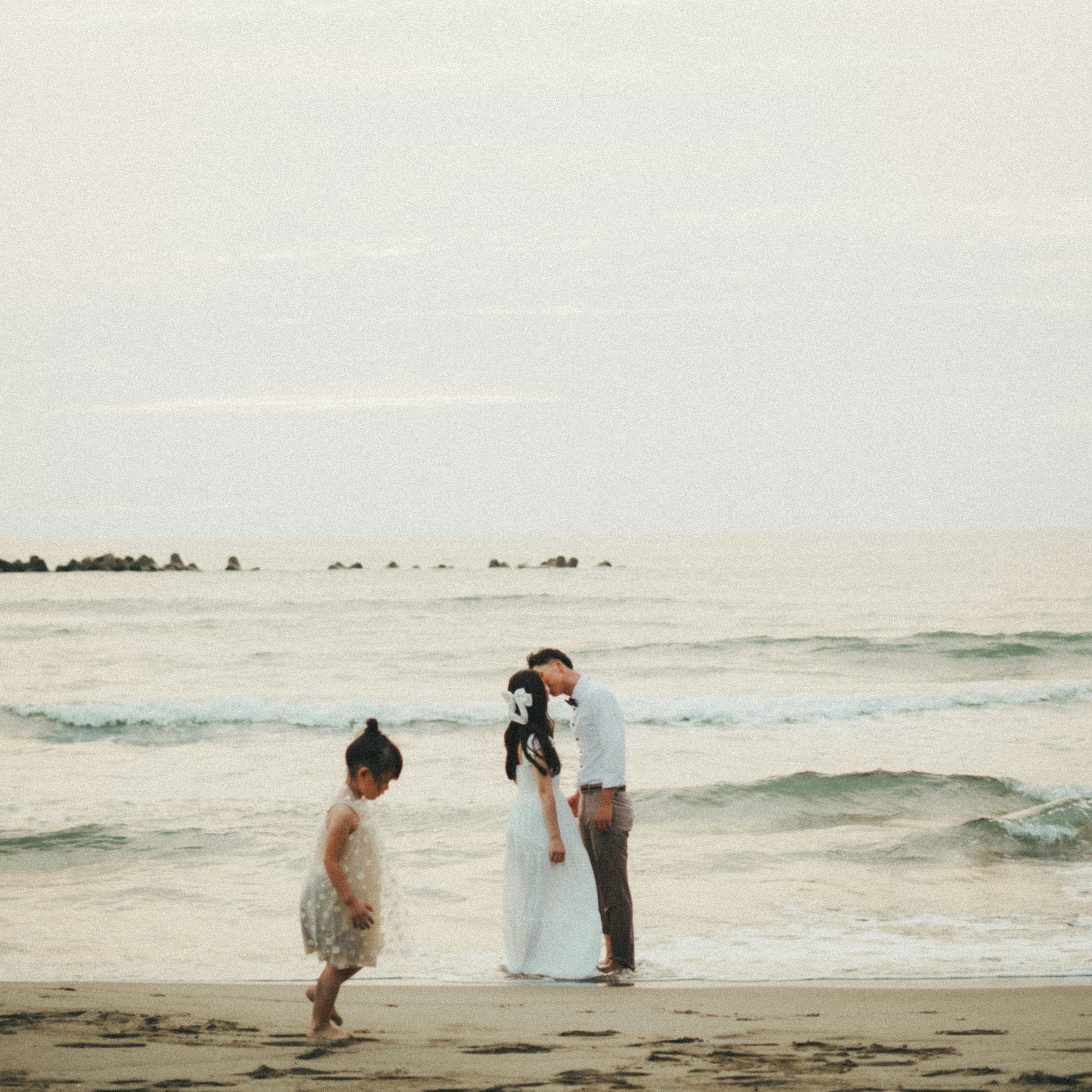 海邊沙灘上新婚夫婦與家人的合影氛圍