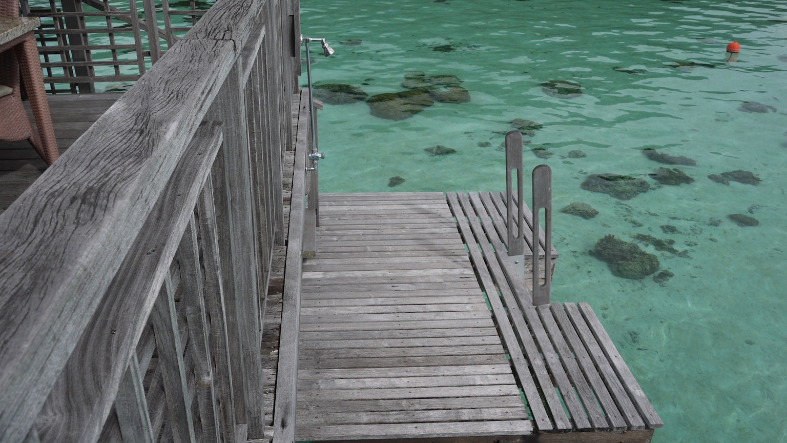 Muelle de madera que se extiende sobre agua clara con rocas visibles
