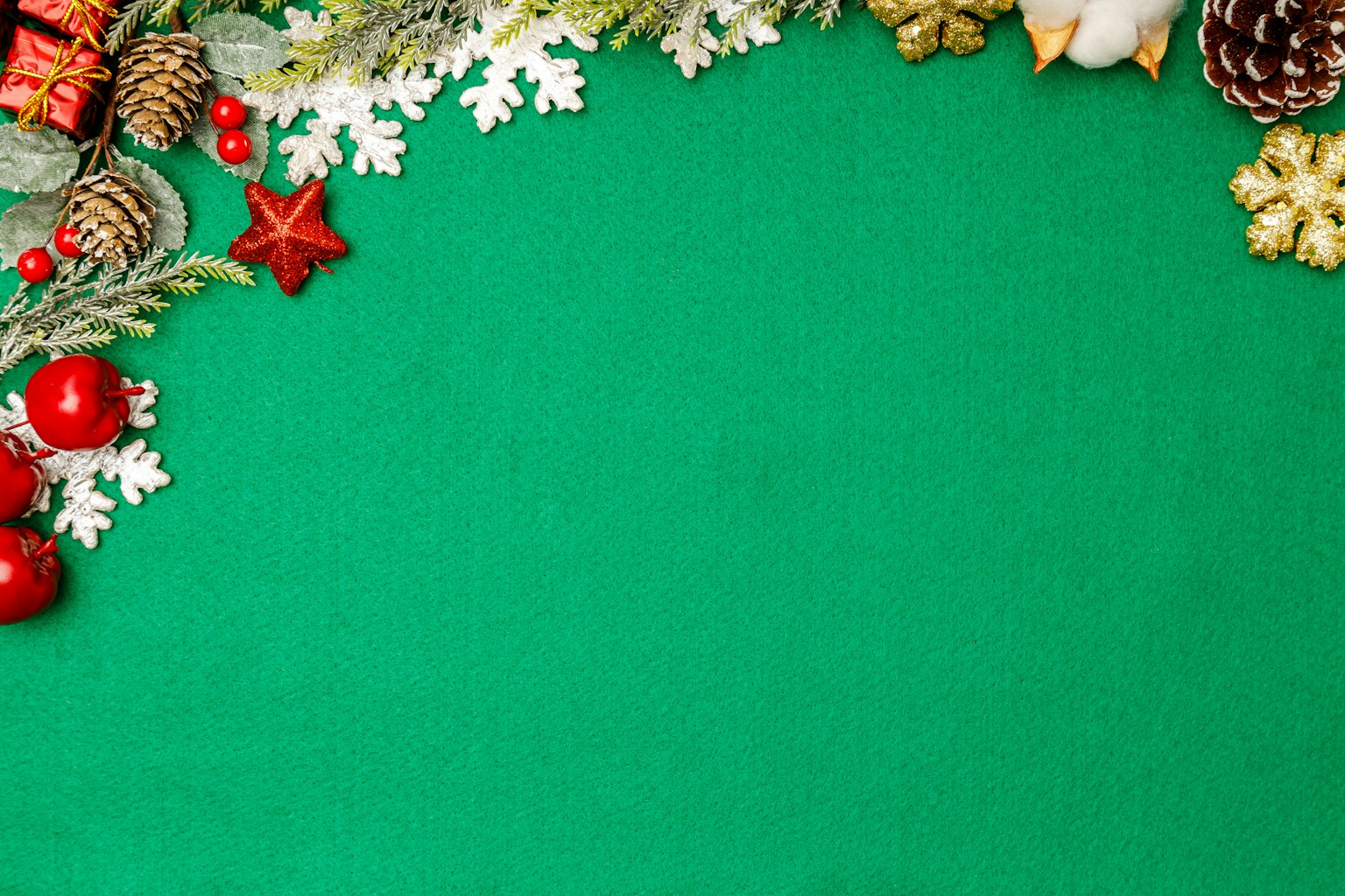 Immagine con decorazioni natalizie su uno sfondo verde tra cui pigne palline rosse fiocchi di neve e ornamenti a stella