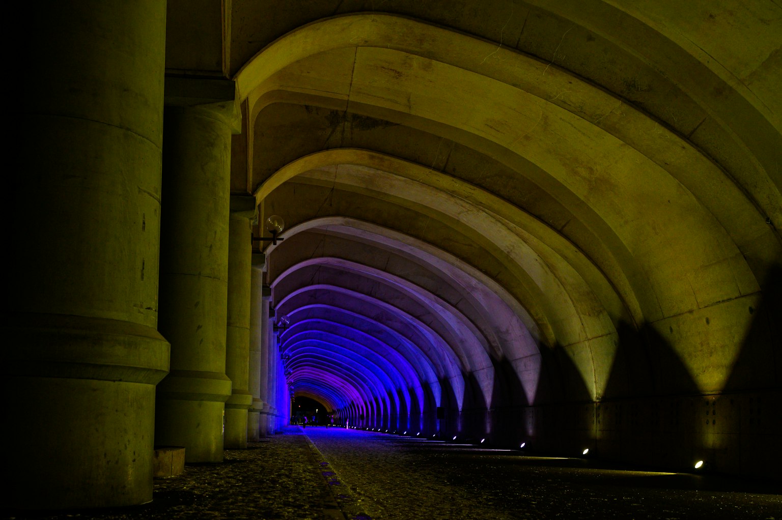 Intérieur d'un tunnel en forme d'arc illuminé de lumières bleues et jaunes