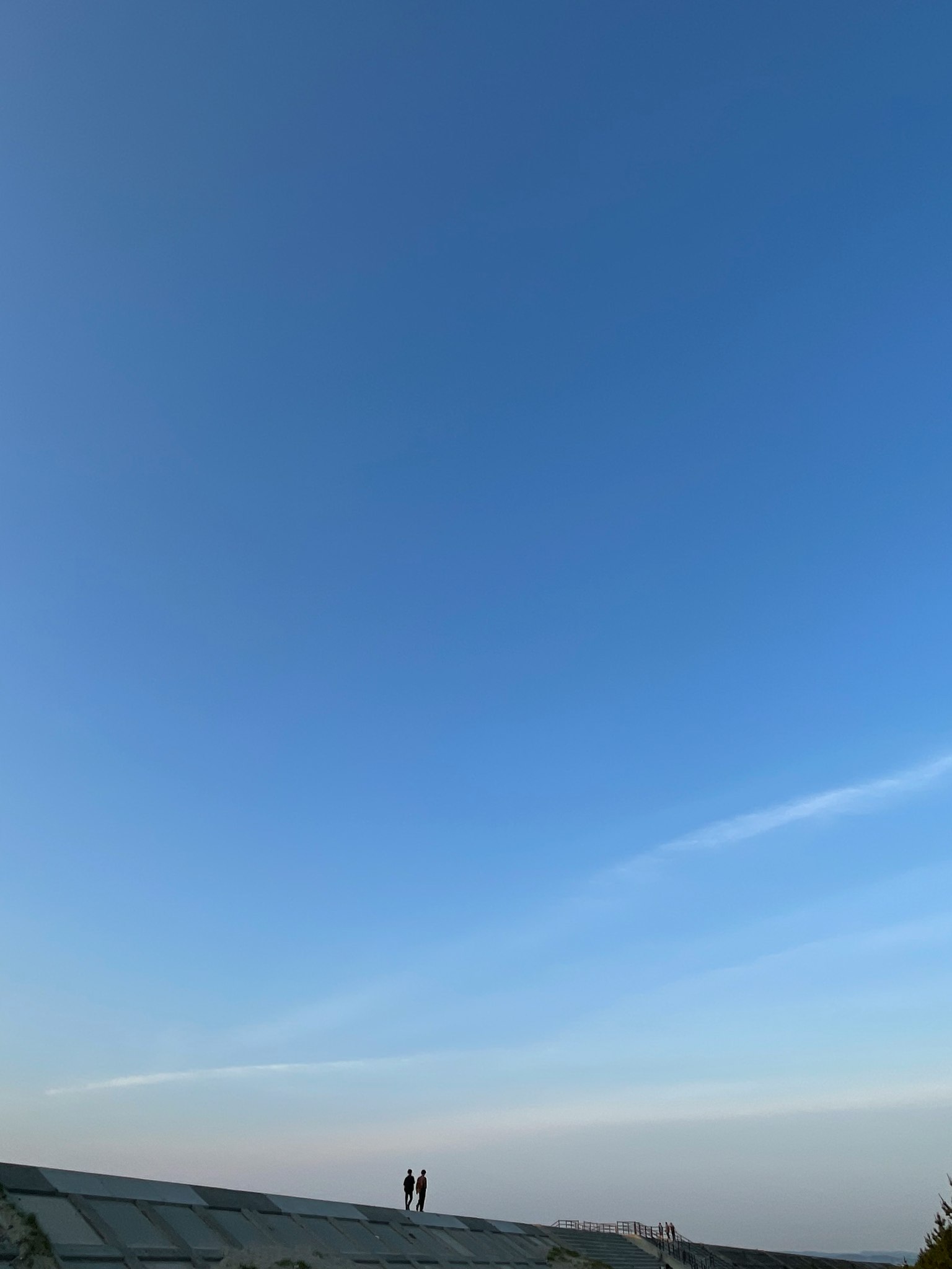 Silhouette de deux personnes se tenant sous un ciel bleu