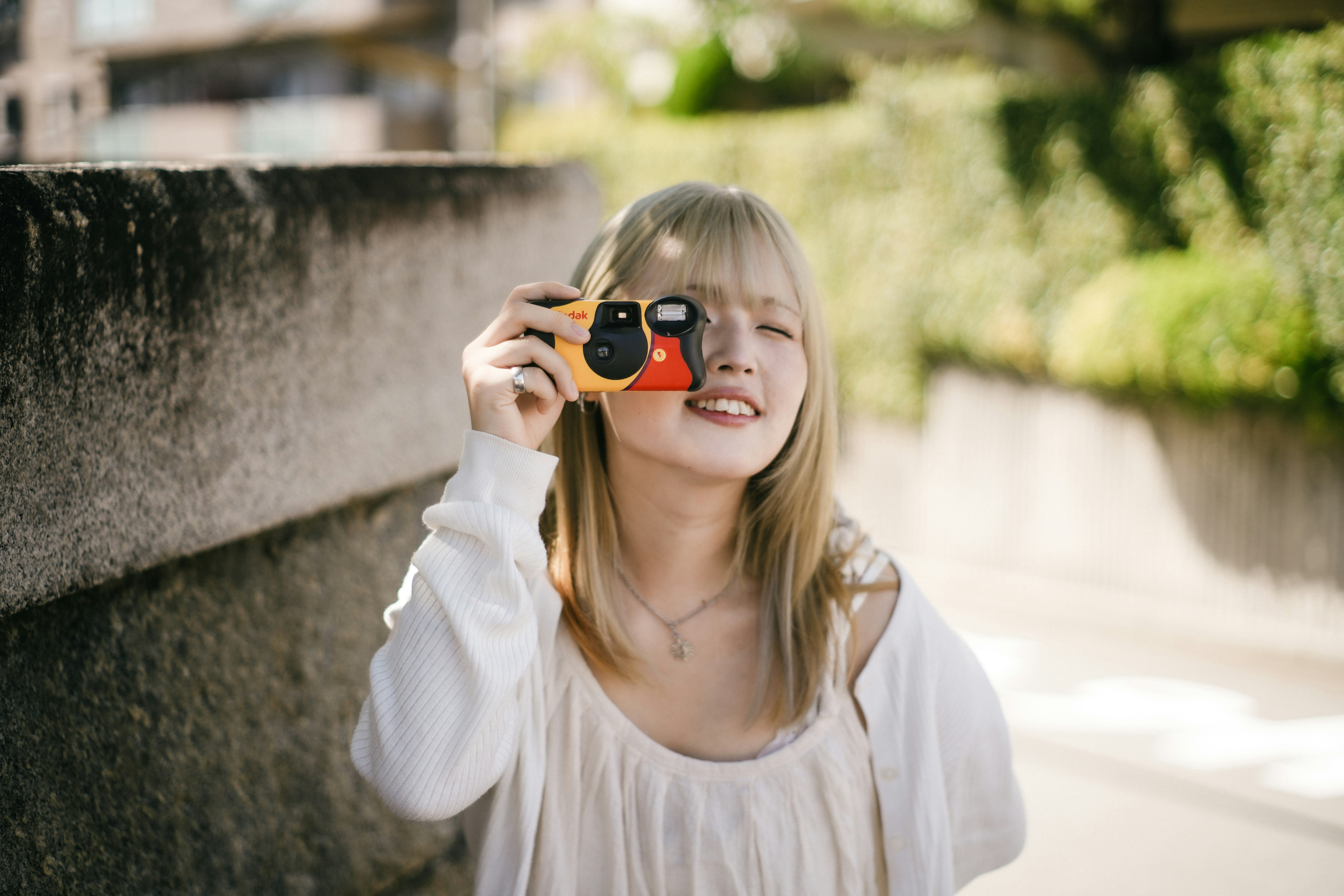 woman holding a camera along a wall