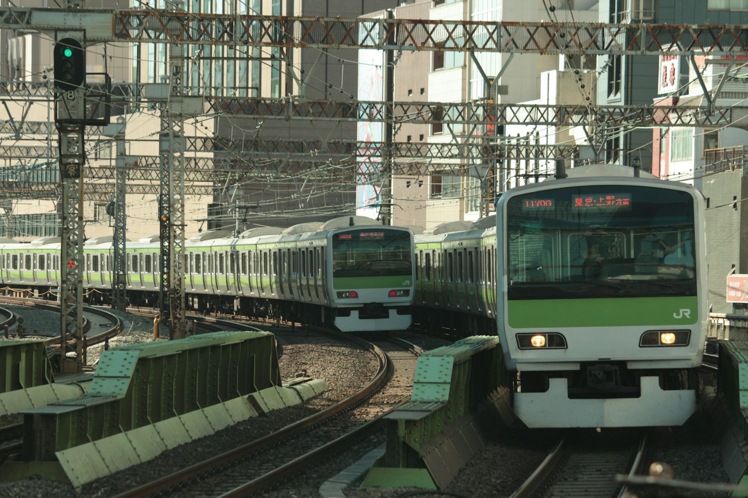 Urban railway scene with green trains crossing each other