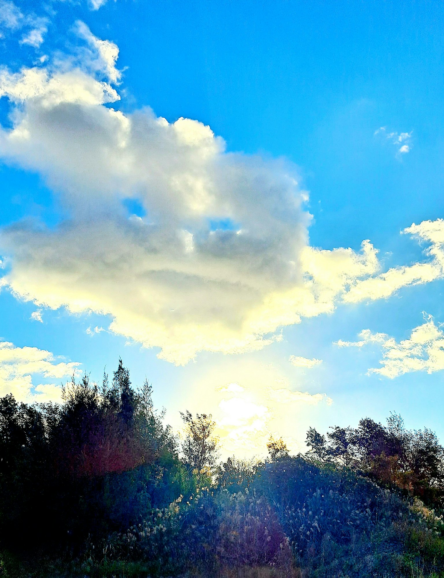 Pemandangan dengan awan dan sinar matahari di langit biru