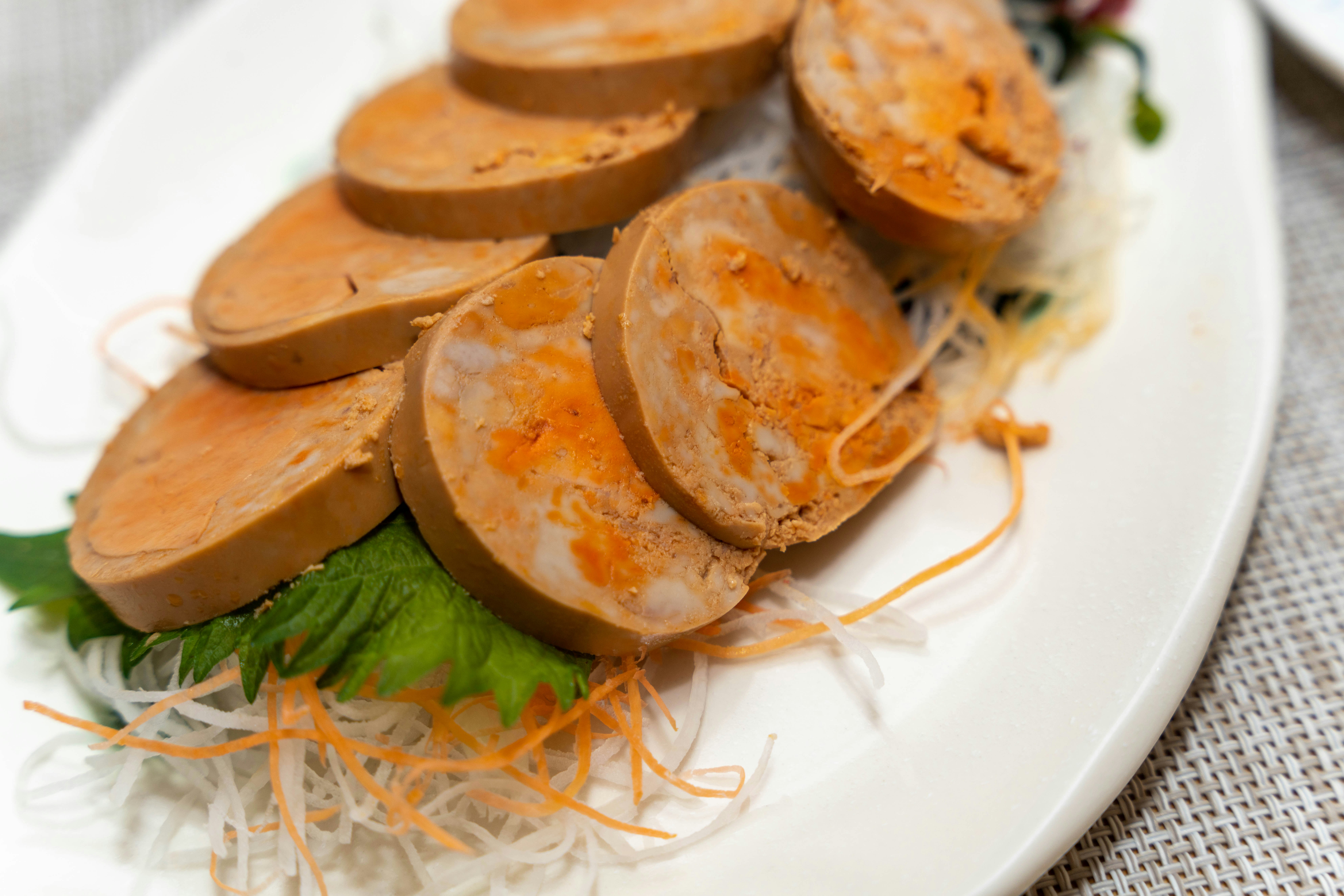 Sliced meat roll presented on a plate with colorful vegetables garnishing