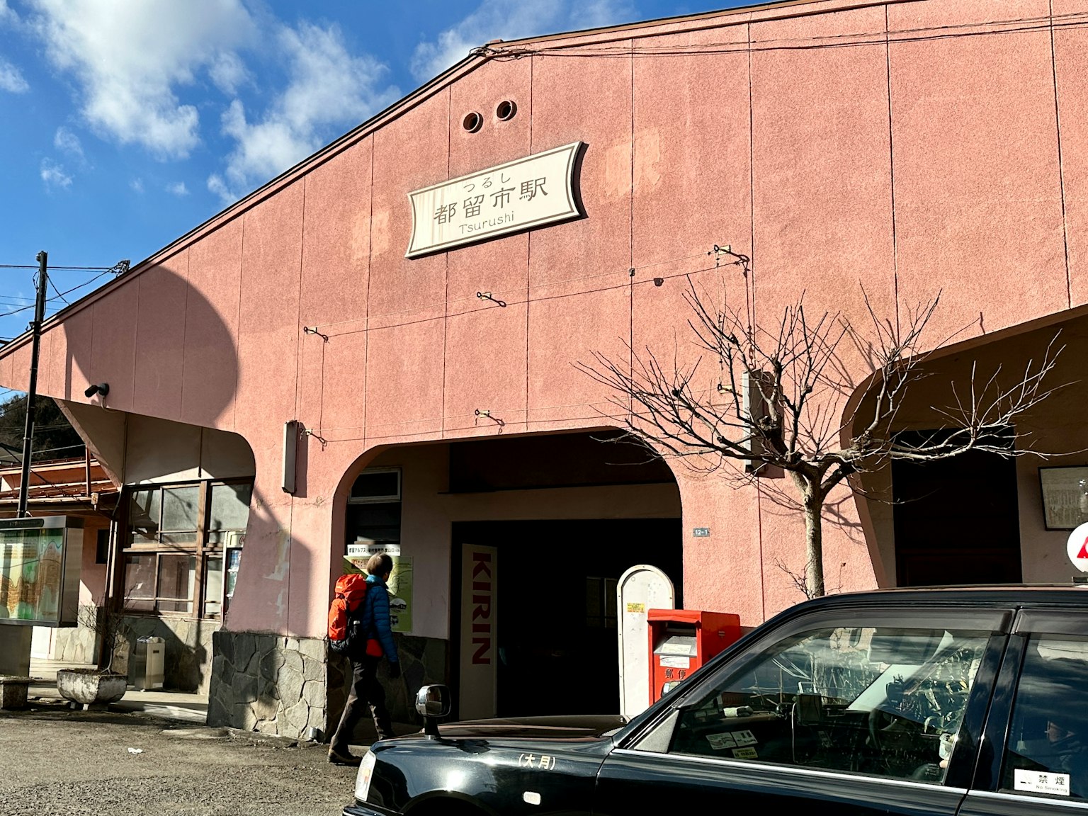 一座粉色外观的火车站建筑和一个路过的人