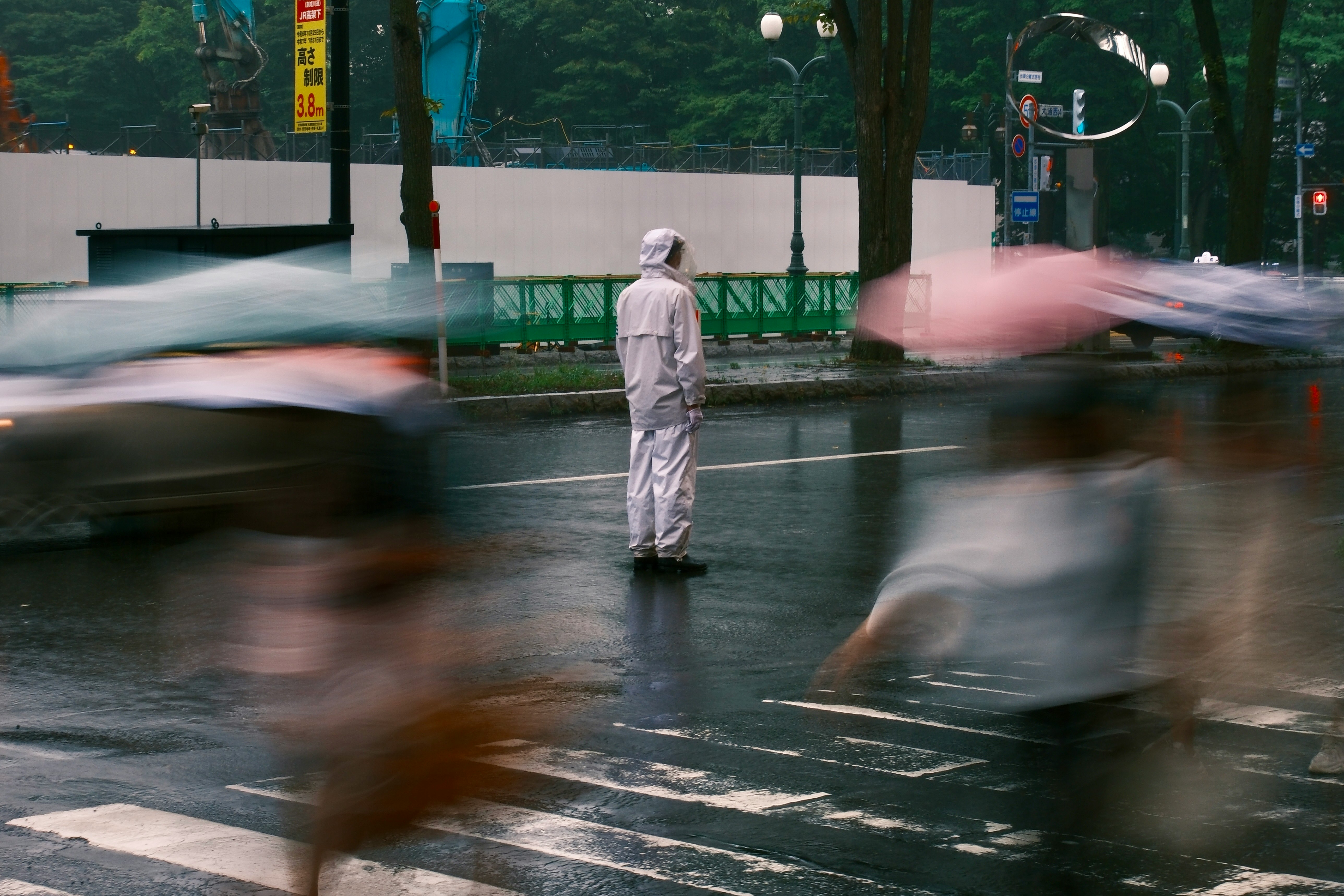 雨の街で白い服の人物が立つ交差点