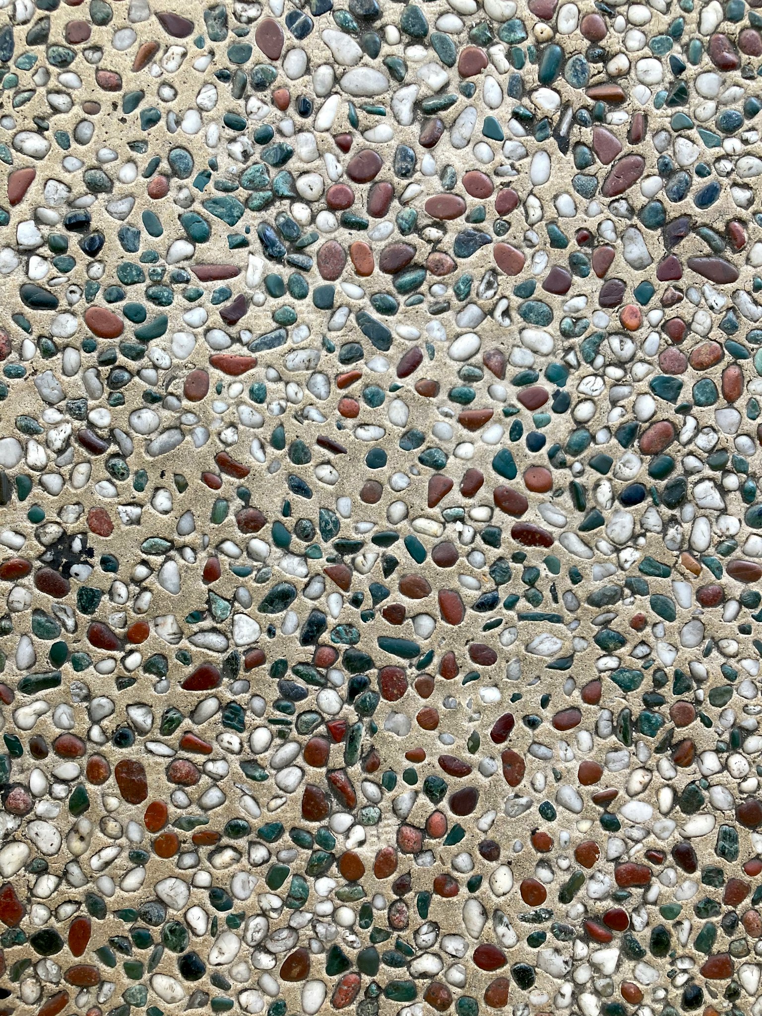 Surface of concrete with various colored pebbles embedded