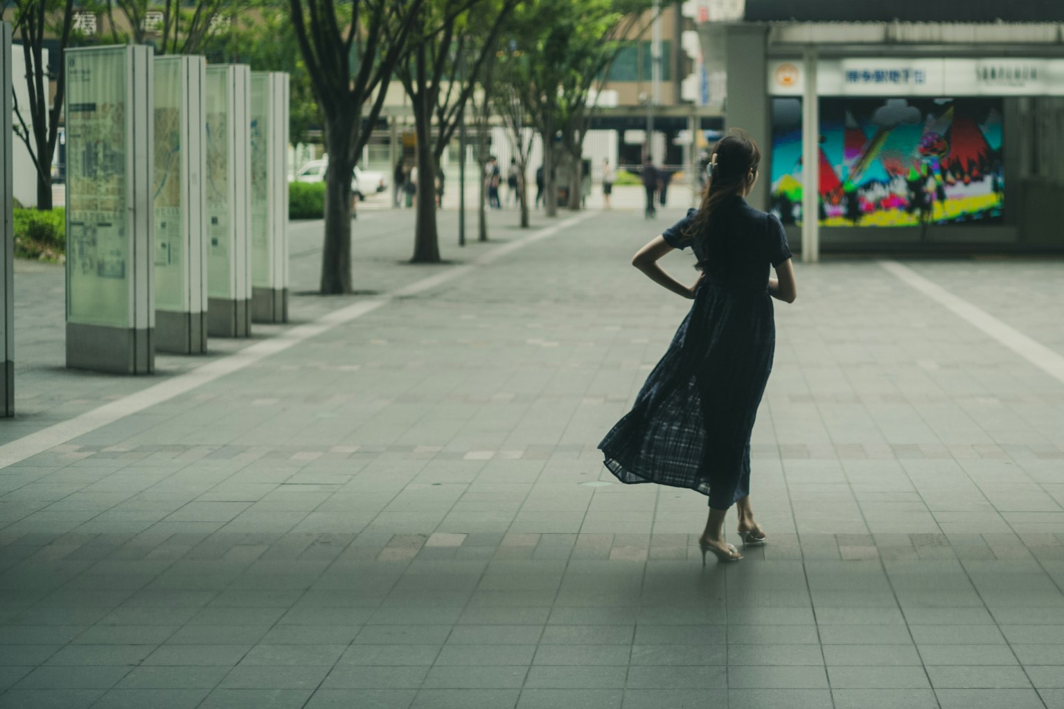 A woman in a black dress walking in an urban area