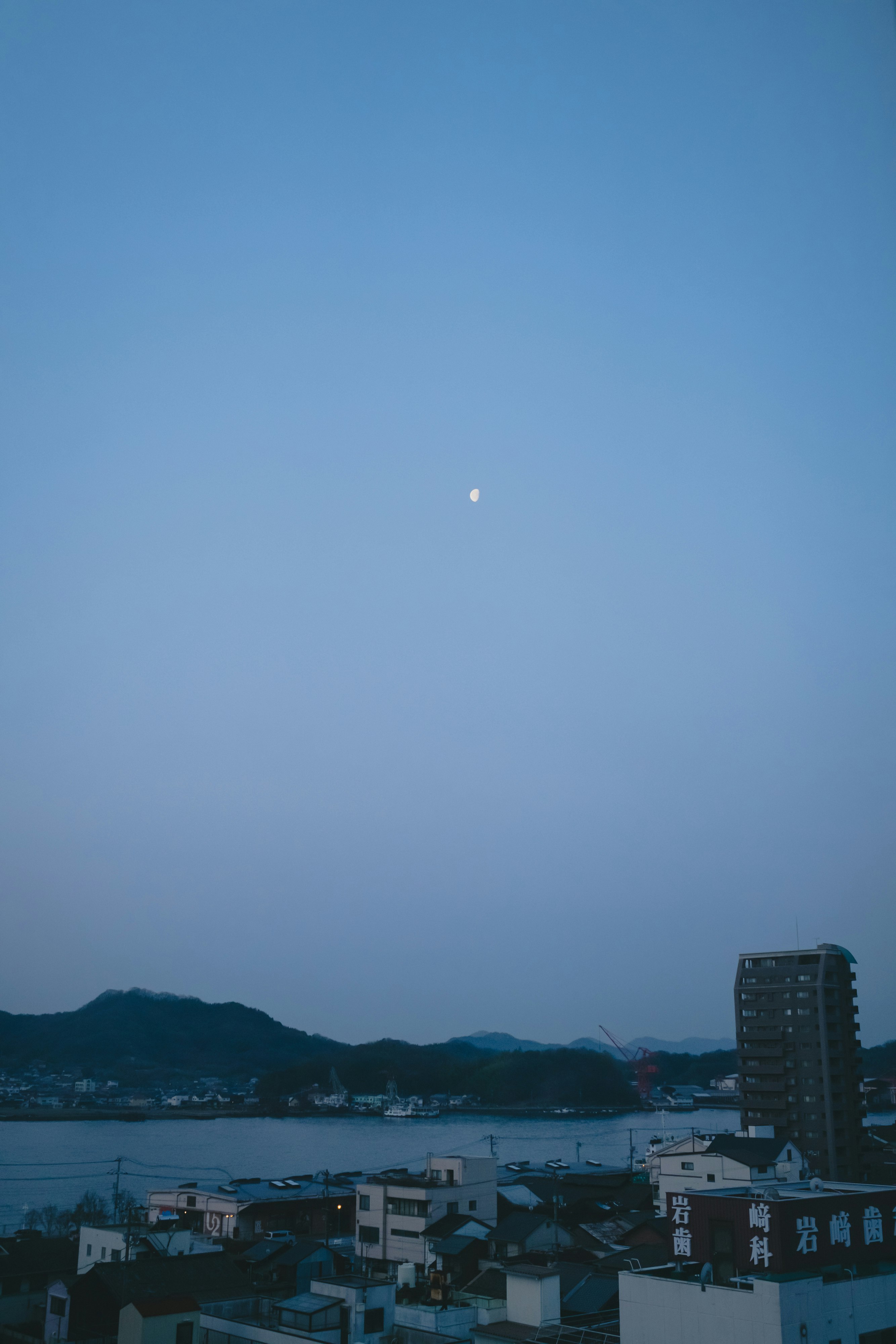 夜明けの海沿いの街並みと山並み