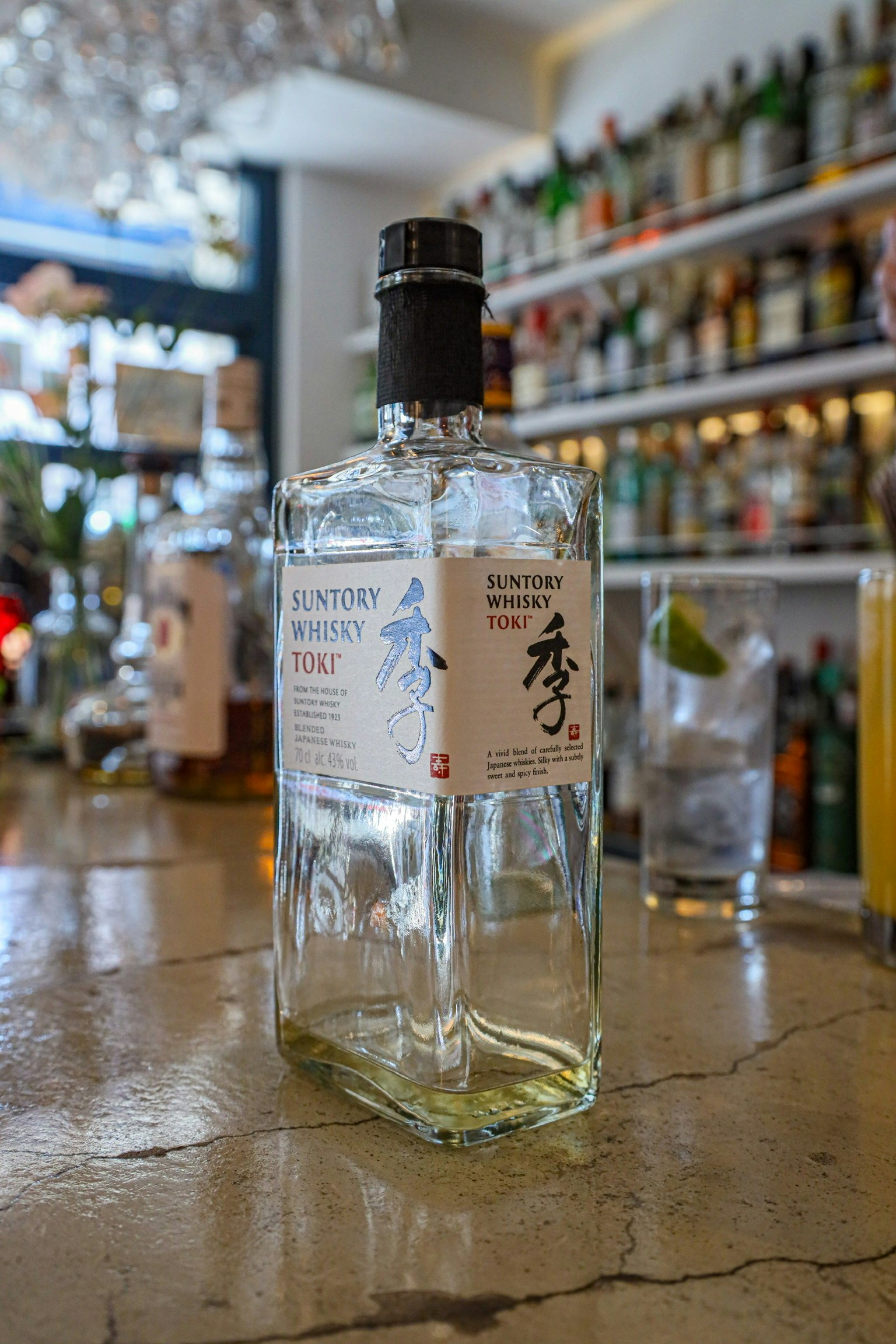 Bouteille de saké japonais vide sur un comptoir de bar avec un fond flou de bouteilles de liqueur