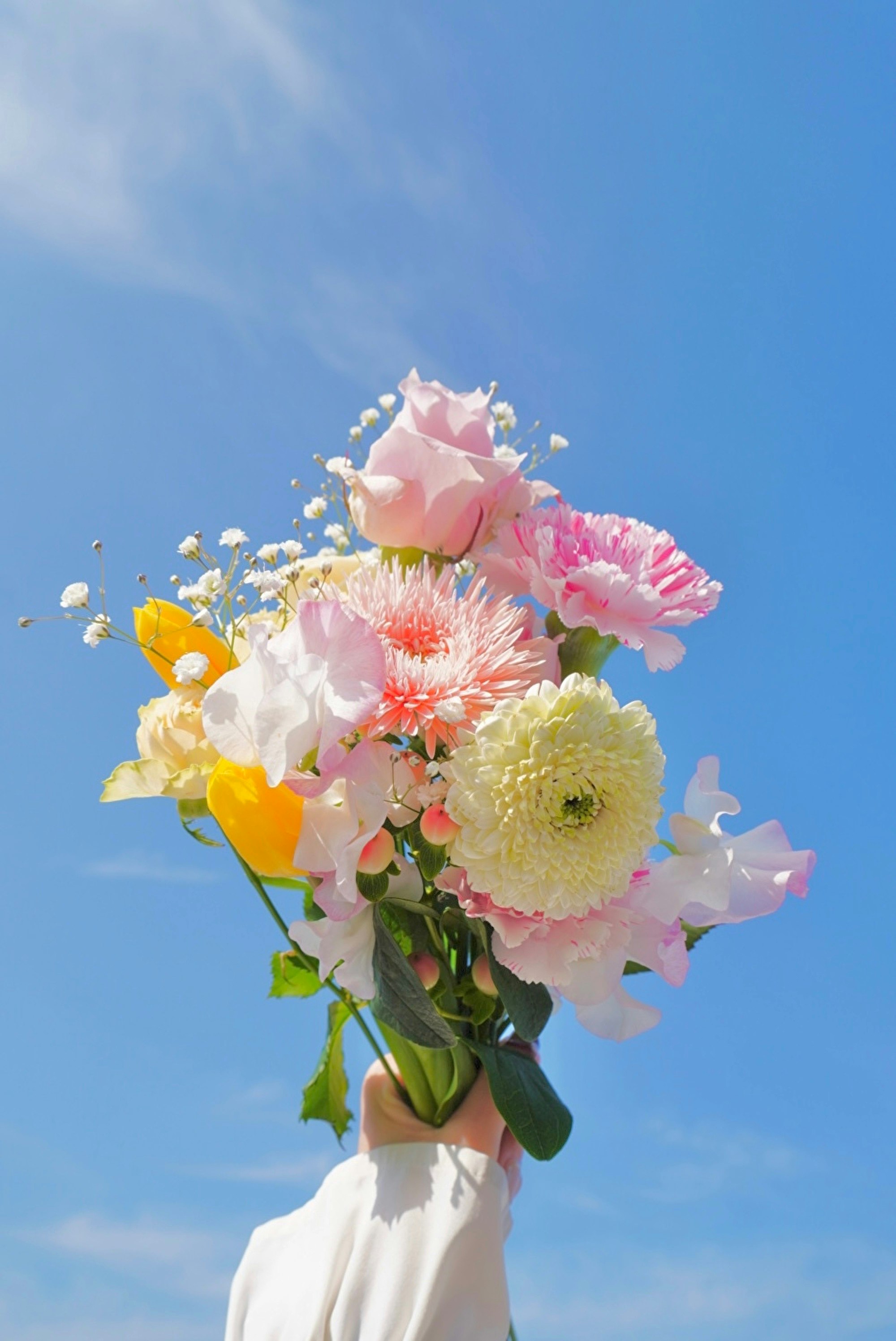青空に花束を掲げた手元の一枚