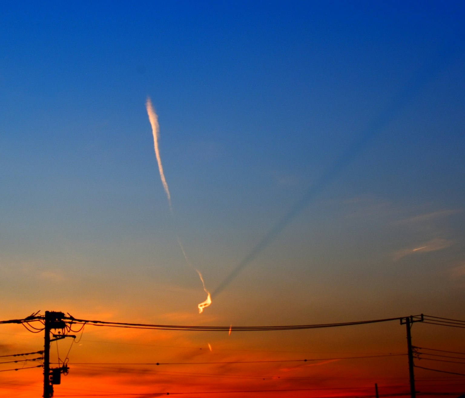 Wunderschöner Sonnenuntergangshimmel mit dünnen Wolken und Stromleitungen