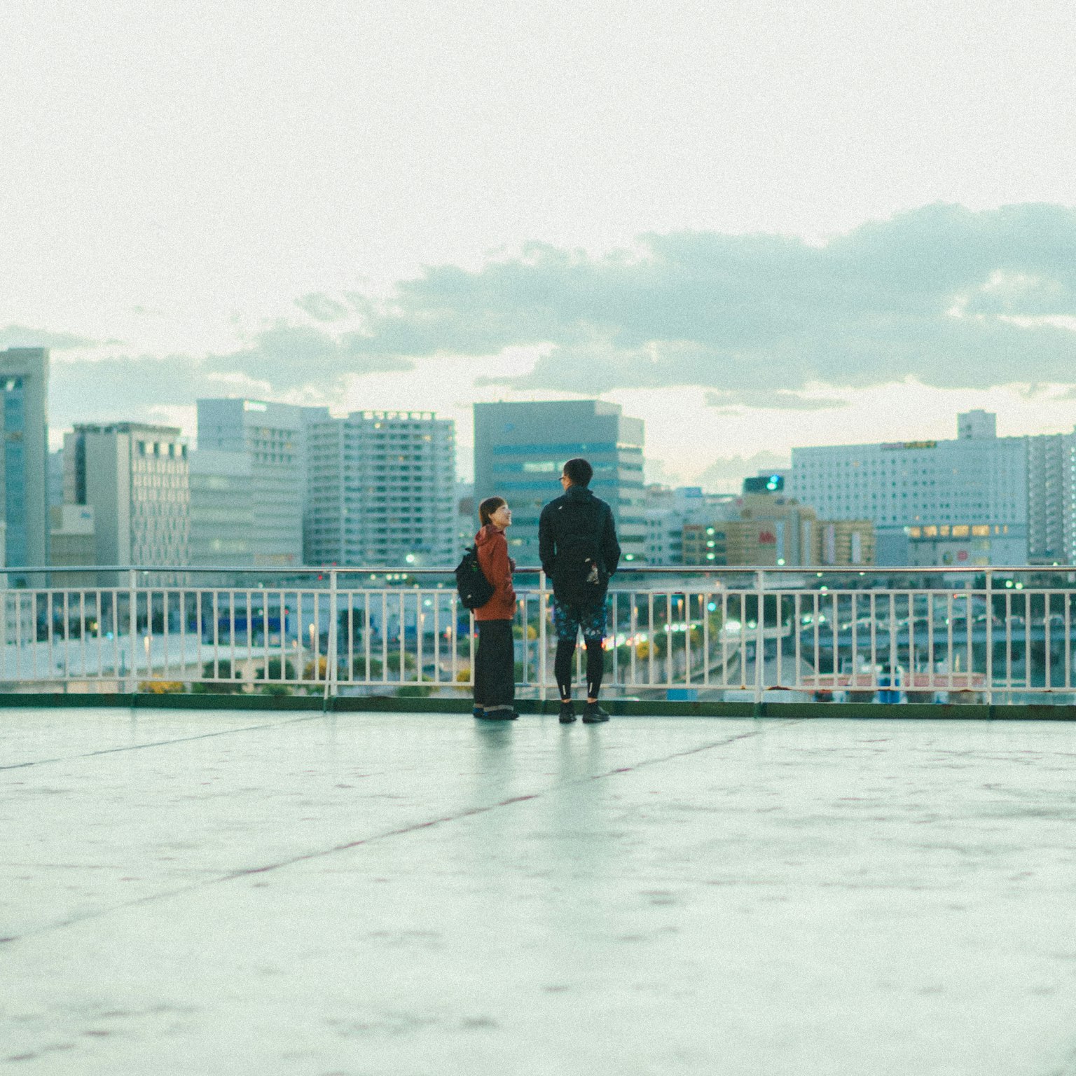 都市の景色を見つめる二人の人物と高層ビル群