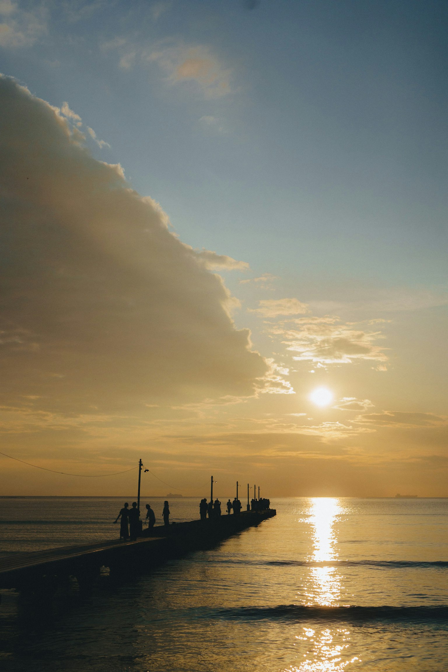 Silueta de un muelle con la puesta de sol reflejada en el mar