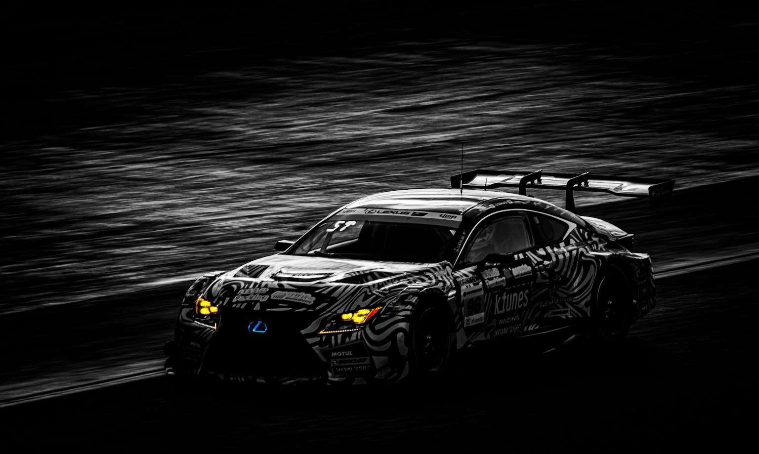 Coche de carreras negro y deportivo acelerando a través de un fondo oscuro