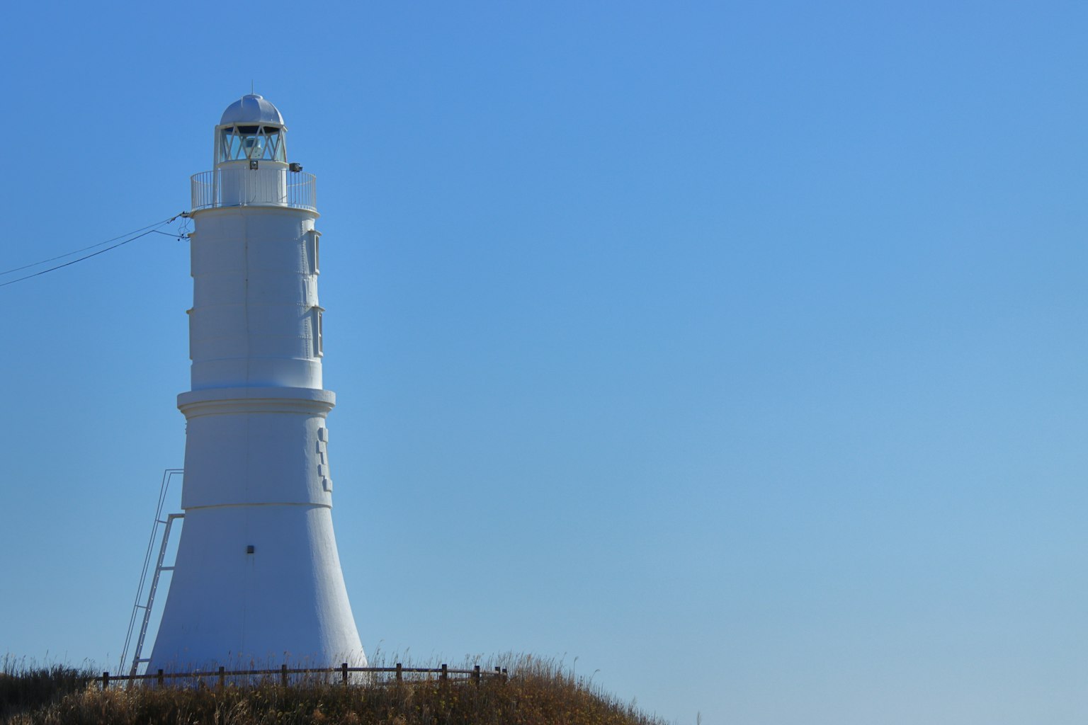 Un phare blanc se tenant sous un ciel bleu