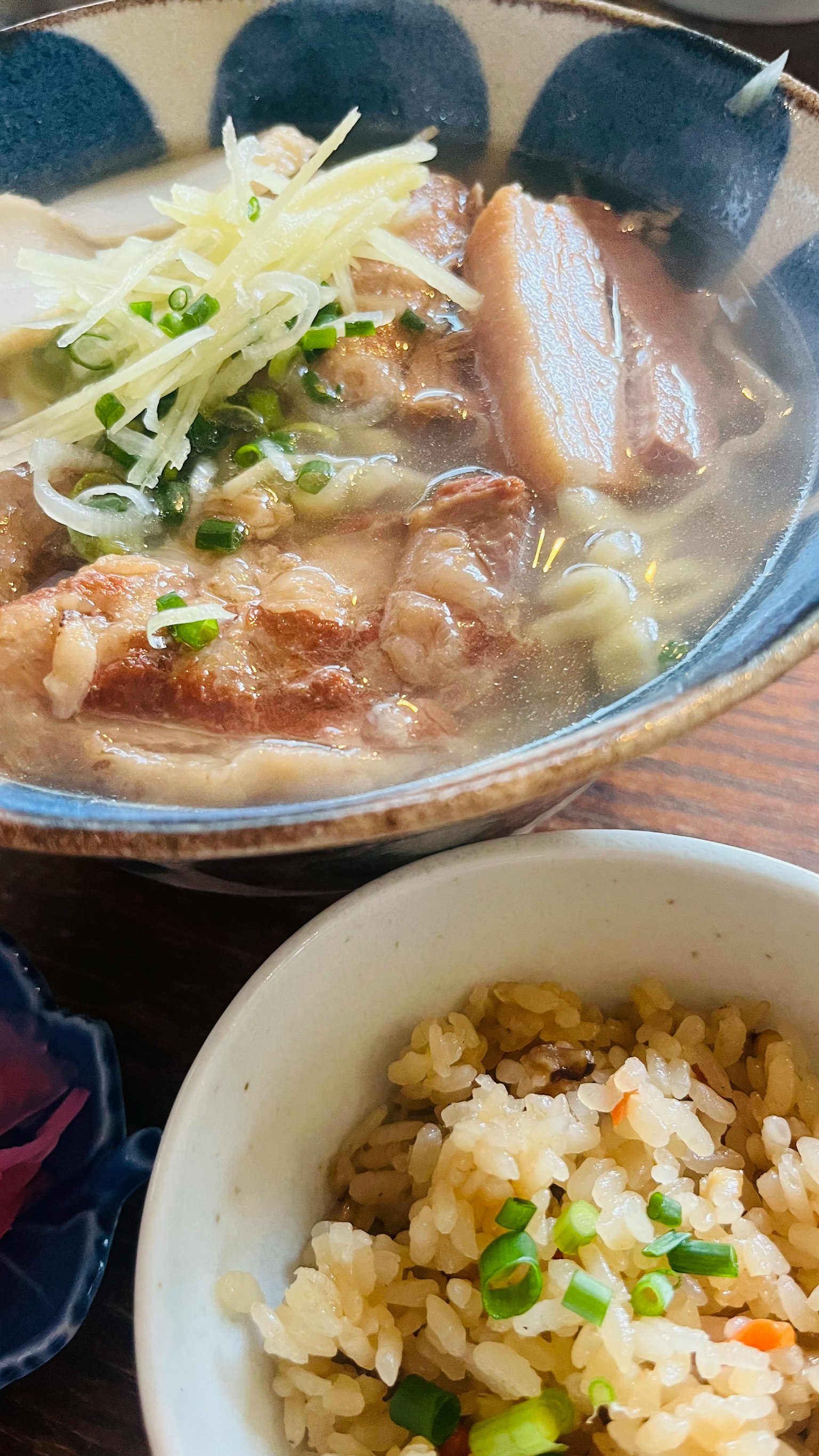 一碗冒 steam 的拉麵，配有切片豬肉和青蔥，旁邊是一碗炒飯