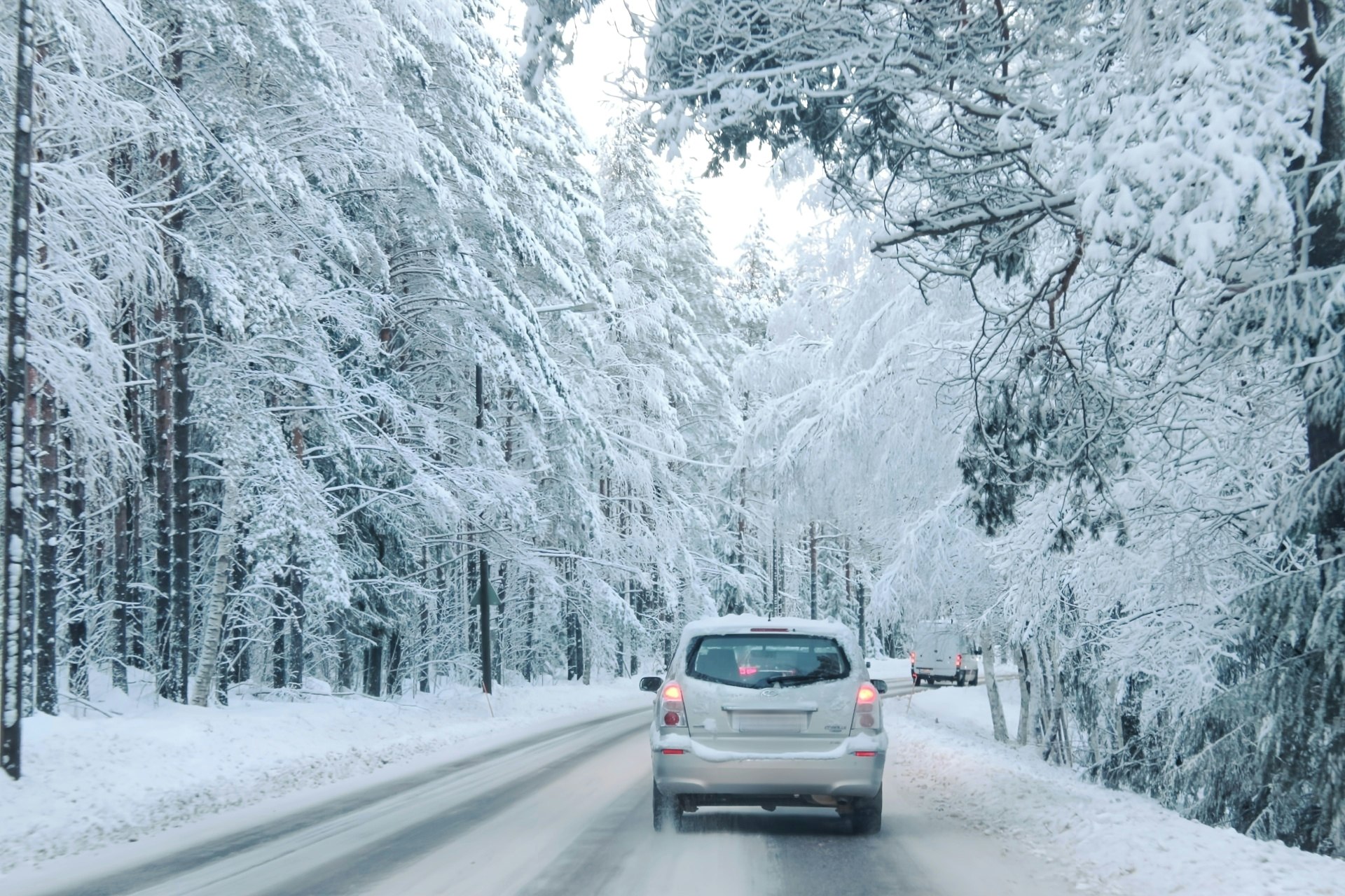 北欧の雪景色の冬道を走る車