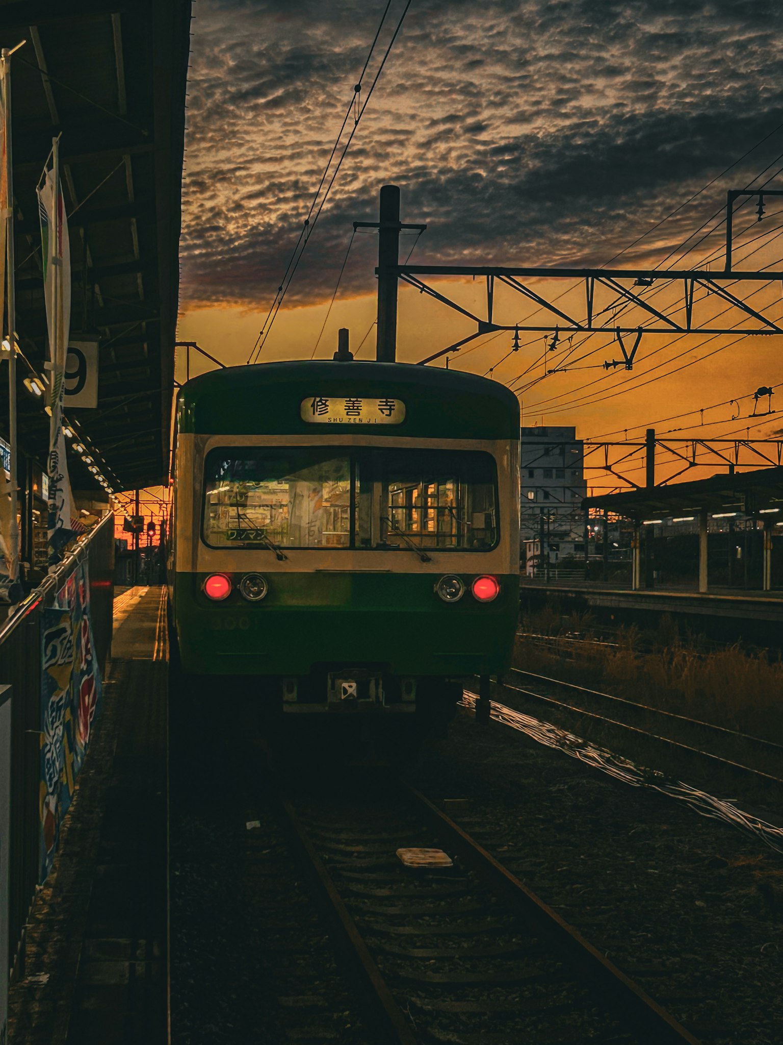 夕焼けの中で停車している緑色の列車 駅のプラットフォームと鉄道が見える
