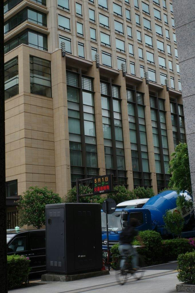 建筑前的街角，蓝色汽车与行人经过