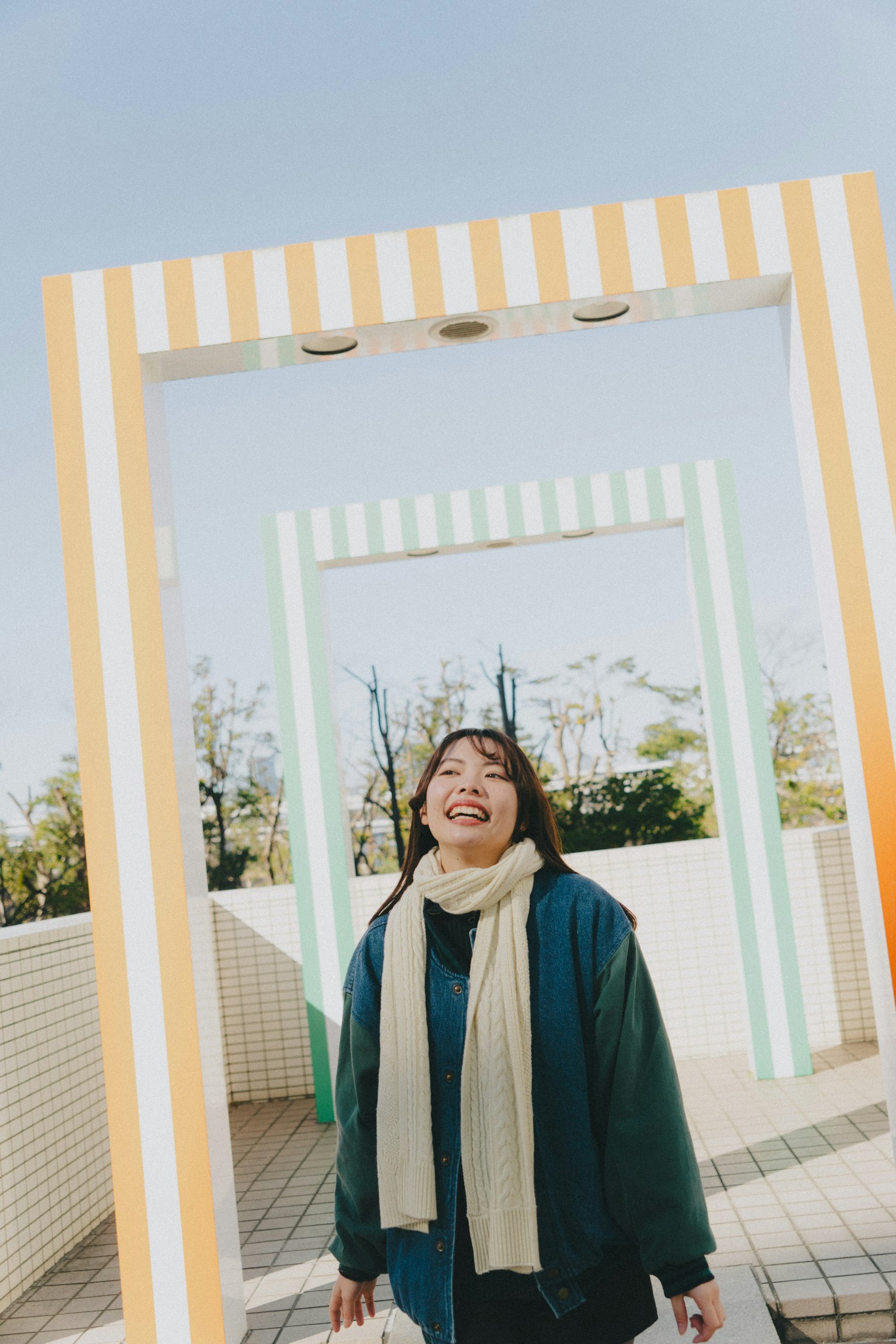 Una donna sorridente si trova tra cornici colorate sotto un cielo azzurro